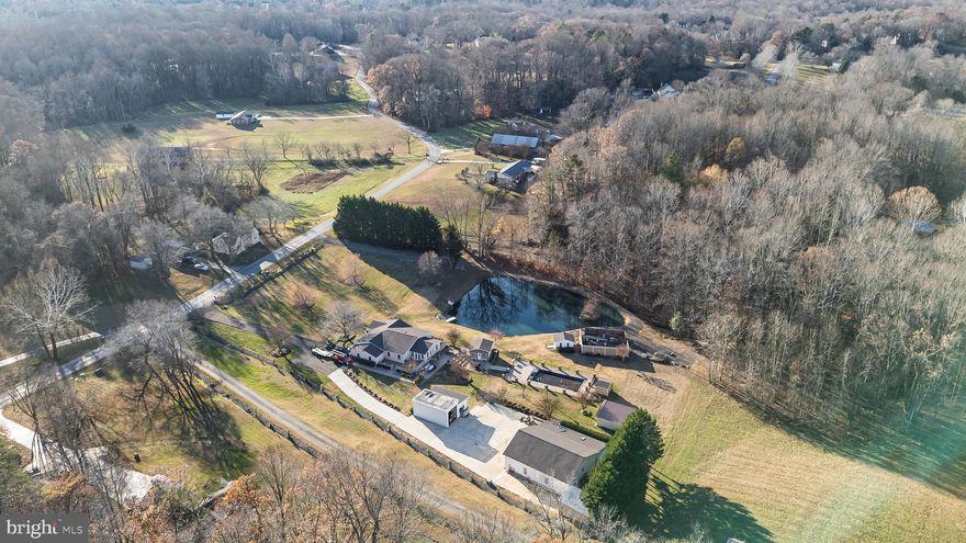 NO HOA! BRING YOUR HOBBIES & TOYS! Welcome to 16970 Teagues Point Road. This rare 3-acre property offers exceptional outdoor amenities, extensive outbuildings and impressive versatility. The land is the true centerpiece of this home. A long private driveway and freshly stained stamped-concrete paths provide smooth access to every area of the property. There are five total outbuildings, including a fully equipped pool house with a kitchenette and mini-split system, a fenced in-ground pool and three oversized garage bays ideal for trucks or an RV. The garage bays include a car lift and built-in cabinetry. Attached to the garage is a separate 1-bedroom, 1-bath dwelling with a full kitchen and pellet stove, offering excellent guest space or income potential. A large stocked pond, filled with catfish, bluegill, bass and more, feeds the front yard sprinkler system and adds natural beauty to the grounds. An accessible courtyard with an outdoor fireplace completes the outdoor amenities and provides an inviting space for entertaining or relaxing. Inside, the home continues to impress. Multiple additions create a comfortable and functional layout. The main level opens with a flexible room that can serve as a bedroom or office. The updated kitchen features granite countertops, stainless steel appliances and freshly painted cabinetry. It flows into a spacious living room that works well for everyday use. A bright sunroom or office sits toward the back of the home and offers abundant natural light. Additional highlights include a large laundry room and an updated hall bath with modern finishes. The primary bedroom features double closets and a generous en-suite bathroom. Three additional bedrooms provide excellent space for a variety of needs. Recent improvements include a new roof, a newer HVAC system and a recently pumped septic system, which all offer added peace of mind. With its impressive outdoor amenities, versatile outbuildings and thoughtfully improved interior, 16970 Teagues Point Road is a standout property that offers space, function and endless possibilities. Seller selling as-is.