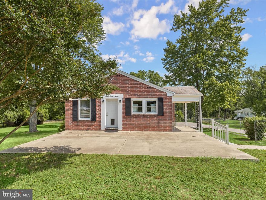 If you’ve been looking for a ranch-style home with a generous, fully fenced one-acre lot and flexible living spaces, this property offers just that. With multiple entrances and a practical layout, it’s well-suited for a variety of lifestyles, including co-living or multi-generational setups.  The front entrance opens into a room that can function as either a living space or one of the home's three bedrooms—ideal for adapting to your needs. The kitchen, with views of the front lawn, includes a second entrance leading to a side porch, while a cozy dining alcove features built-in glass-front cabinetry for added charm and storage.  Down the hall, you’ll find a primary bedroom with en suite bath, a second bedroom, and a full hall bath. The lower level expands the living space with a family room anchored by a stone-surround fireplace, plus a powder room, laundry area with hook-ups and storage cabinets, and a utility/storage room.  What truly sets this property apart is the flat, fenced acre of land—perfect for pets, gardening, or simply enjoying the outdoors beneath mature shade trees. Additional features include a covered front patio and walkout lower level, enhancing the home’s livability.  Conveniently located near I-695, I-70, and a variety of shops and restaurants, this home offers simplicity, space, and room to grow.