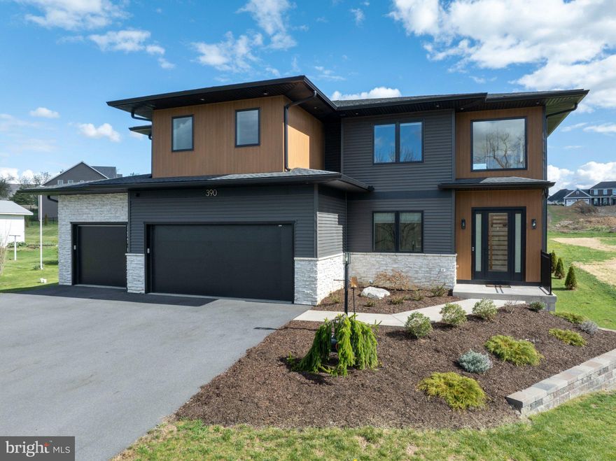 Completed in 2024, this striking modern home offers over 3,200 square feet of light-filled living space on just over half an acre. Clean lines, warm wood tones, and expansive windows define the design, creating a residence that feels intentional, elevated, and effortless to live in. The main level features a dramatic open-concept living area with soaring ceilings and wide-plank hardwood floors. A wall of windows floods the space with light, framing a built-in window seat and a striking modern stove. The kitchen anchors the home with an oversized island, custom cabinetry, and high-end appliances—designed to perform as beautifully as it looks. The first floor office could easily be used an additional bedroom, already equipped with a Murphy bed and adjacent full bath! Upstairs, the primary bedroom is bright and expansive. The attached bath offers a double vanity and tiled walk-in shower. Three additional bedrooms and well-finished baths provide flexible space for family, guests, or work-from-home needs. The lower level remains unfinished, providing the next owner with the flexibility to design additional living space tailored to their needs—whether a theater, gym, guest suite, or expanded recreation area. Outside, the fenced yard provides privacy and room to relax or play. A covered rear patio creates a beautiful outdoor space for dining, grilling, or unwinding. A three-car garage and whole-house generator add everyday convenience and peace of mind.