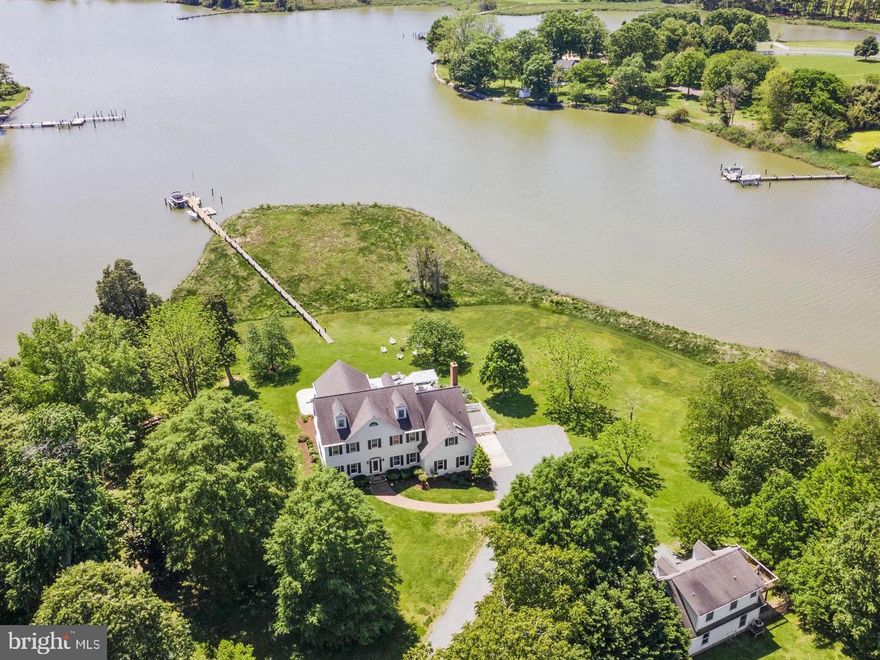 This beautiful waterfront estate with broad views of Plaindealing Creek is being sold furnished (except for owners personal belongings and some artwork) and was tastefully decorated by Come by Chance out of St Michaels. Sited on 21 acres (zoned agricultural) the property provides the utmost in privacy, and features a waterside pool, hot tub, and pier with lift and 3+ MLW. The main house offers spacious living areas boasting elegance and charm, high ceilings, gleaming hardwood floors, and bespoke finishes.  The open floor plan on the main level features a gourmet kitchen with stainless appliances and center island, a large family room with cathedral ceiling and wood-burning fireplace, an expansive enclosed sunroom overlooking the pool and creek, and formal living room and dining room. In addition, there is a guest bedroom (could be used as an office too) and full bath. On the second floor, the primary suite is a rare treat featuring an ensuite sitting/reading room with panoramic water views, luxurious primary bath with soaking tub, separate  shower, double vanities, and his/hers walk-in closets. Two additional bedrooms, a large hall full  bath, laundry facilities, private nook (currently used for additional bed space), and open landing overlooking the family room complete the second level. The third floor is completely renovated, has shiplapped walls, and includes a full bath. Finished with multiple bunk areas, this incredible space provides great fun for kids and guests. An attached 2-car garage and small dog run complete the main residence. Adjacent is a 2-car detached garage with a charming studio apartment above, boasting hardwood floors, bedroom, kitchen and living areas, full bath, and outdoor deck. An additional 1-bay garage/shed is also onsite providing ample storage for boat, tractors, etc. Whether you're enjoying the tranquility of outdoor living or hosting lively gatherings with friends and family, this property offers the ultimate of being on the Eastern Shore. Note: The lane is owned by this property though the two neighbors on the left have 'right of way'.