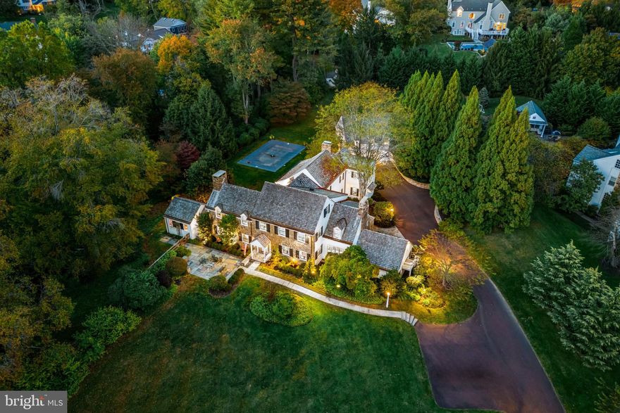 This property is 4 acres, 2 separately  deeded lots. The home sits on 2.5 acres and the lot next to it is 1.5 acres. Drive down one of Bryn Mawr’s most desirable tree-lined streets and turn into the long driveway lined with lamp poles and specimen plantings. The stately stone manor home with white siding, black shutters and slate patios front and rear say you’ve arrived. This fully updated classic Pennsylvania farmhouse sits on two fenced-in parcels totaling more than 4 acres in the heart of the Main Line, in the coveted Radnor School District. 
This 6000 + Okie farmhouse, a Colonial Revival main home, was built in 1942 and redesigned for modern living in 2014 by architect Ann Ledger of Wayne. It (main house)features 5 bedrooms, 5 full and 2 half baths on 2.5 levels, plus a finished lower-level bonus room and a 1-bedroom, 1 bath studio apartment/guest house  above the detached garage. Inside you’re surrounded by rich architectural features from past and present—from arched doorways, Dutch doors with rustic wrought-iron hardware, beautiful hardwood floors and 3 fireplaces, to built-in lockers in the mudroom and bookshelves in both offices, marble bathrooms with seamless shower doors and walk-in closets everywhere. Throughout, generous windows offer great views of the property from every angle and fill the home with light.
On the main level, the foyer opens to stairwells to the upper level and finished lower level and features a formal powder room. Both the living room and great room feature fireplaces. French doors in the living room open to a slate patio. The equally spacious great room has split doors to the back patio and the mudroom addition and opens to the kitchen and breakfast room as well. A family room provides additional informal gathering space and a 2nd stairwell to the upstairs hallway. Two offices—one off the kitchen and the other opening to the backyard—feature built-ins in beautiful shades. 
A butler’s pantry—fully equipped with a beverage refrigerator, dishwasher and icemaker—services both the dining room and the center-island kitchen—a chef’s delight with Thermador 6-burner stove with griddle and range hood Thermador double wall oven and warming drawer, a farmhouse sink and other high-end stainless steel appliances. Featuring white inset cabinets, a subway tile backsplash and white beadboard ceiling, this cheery space opens to a large breakfast room overlooking the patios and pool. There’s also a door to the driveway area for family members and “backdoor friends.”
On the first upper level, the primary bedroom features a large covered balcony with a gorgeous view of the pool and backyard, as well as two walk-in closets with built-in storage and a luxurious private bath with radiant-heated tile floors, double sinks and high vaulted ceilings—part of the 2014 addition. Three large additional bedrooms with en suite baths were also part of the renovation, and a laundry room with built-in cabinets and countertops adds convenience. On the second upper level, a large room and full bath could be used as a playroom or additional bedroom. On the lower level, a finished bonus room with fireplace provides flexible space to suit your family’s style.
The main-level mudroom has tile floors, an informal powder room and walk-in closet, along with built-in cubbies, and a bar with refrigerator to serve the pool area. Picture yourself sitting by the in-ground pool/spa listening to the soothing sound of the Kirk’s Run creek, which runs alongside the property. Off the pool area, a detached two-car garage includes a one-bedroom studio apartment with full bath and kitchenette for your guests’ convenience and your privacy.
Gorgeous inside and out, this classic residence offers the best of town and country living just three miles from both the Villanova and Bryn Mawr train stations and within walking distance of the prestigious Agnes Irwin School.