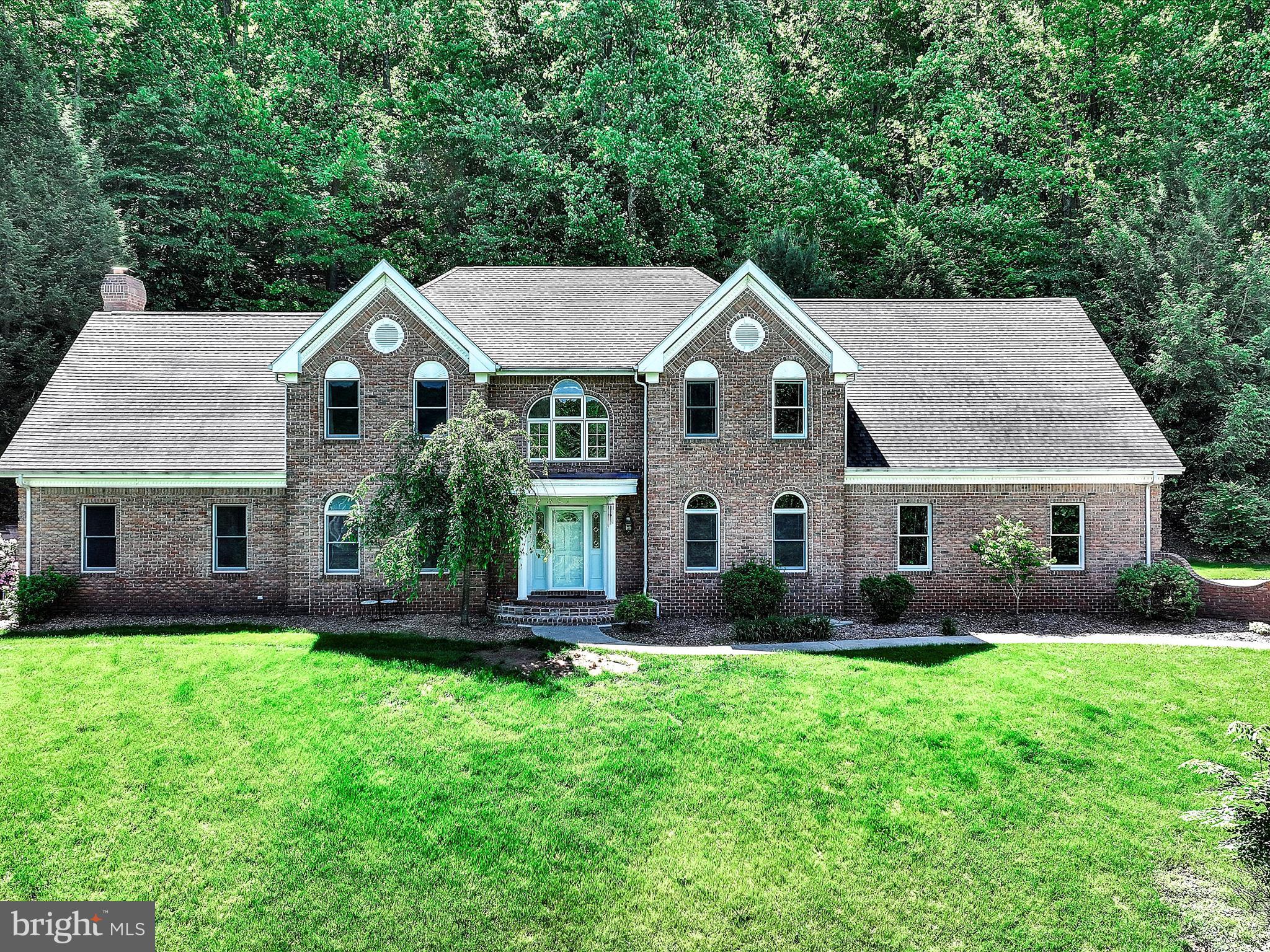 As you turn onto the private drive and pass the tranquil stream, you will immediately be captivated by the breathtaking beauty of this estate situated on over 7 private acres. A spacious driveway welcomes you, offering ample parking for all your vehicles and recreational toys. The home features a 3 car side entry garage with oversized doors, perfect for larger vehicles or extra storage. A concrete walkway leads to the stately brick front entrance, setting the tone for the elegance and craftsmanship found throughout the property. Step into a grand 17-foot foyer featuring a stunning curved staircase that sets the tone for this elegant home. To the right, you’ll find a formal living room perfect for entertaining, while to the left, the formal dining room showcases beautiful hardwood floors and flows seamlessly into the gourmet kitchen. The kitchen is a chef’s dream, boasting a massive island with a built-in cooktop and exhaust system, a wall oven/microwave combo, and exquisite cherry cabinetry accented by custom built-ins throughout. Overlooking the kitchen is a spacious family room, offering a bright, open-concept layout. Enjoy the warmth of a dramatic floor to ceiling brick fireplace, vaulted ceilings, and skylights that bathe the space in natural light. The spacious family room overlooks the kitchen, creating a seamless and bright open-concept living area. Anchoring the space is a stunning floor to ceiling brick fireplace, complemented by soaring vaulted ceilings and skylights that fill the room with abundant natural light. A generously sized office provides the perfect setting for a home workspace or homeschool area, offering both functionality and privacy. Up the elegant curved staircase, you’ll find four spacious bedrooms and a large open loft area perfect as a TV room, play space, or easily convertible into a fifth bedroom. The primary suite is truly expansive, offering ample space for all your furnishings and more. Enjoy your own private balcony overlooking the backyard, skylights that brighten the room, and three oversized walk-through closets. The luxurious en-suite bathroom features a tiled shower built for two, a relaxing jacuzzi tub, dual vanities, and built-in heat lamps for added comfort.
Three additional generously sized bedrooms and a full hall bath with another jacuzzi tub complete the upper level. For added convenience, the main-floor laundry includes a second-floor laundry chute.
You won’t believe this incredible finished lower level designed for ultimate fun and entertaining. A boat-turned-bar, beachy décor, and a laid-back Margaritaville vibe make it the perfect party space. Separate TV area included, and everything stays! Plus, a ramp from the garage offers easy access for storage.
The exterior is just as impressive an entertainer’s dream! The oversized heated concrete pool features a separate hot tub for year-round enjoyment. A convenient pool house is perfect for hosting summer gatherings, and ample storage space keeps everything organized all year long. 3 car garage and ample parking in the driveway.
