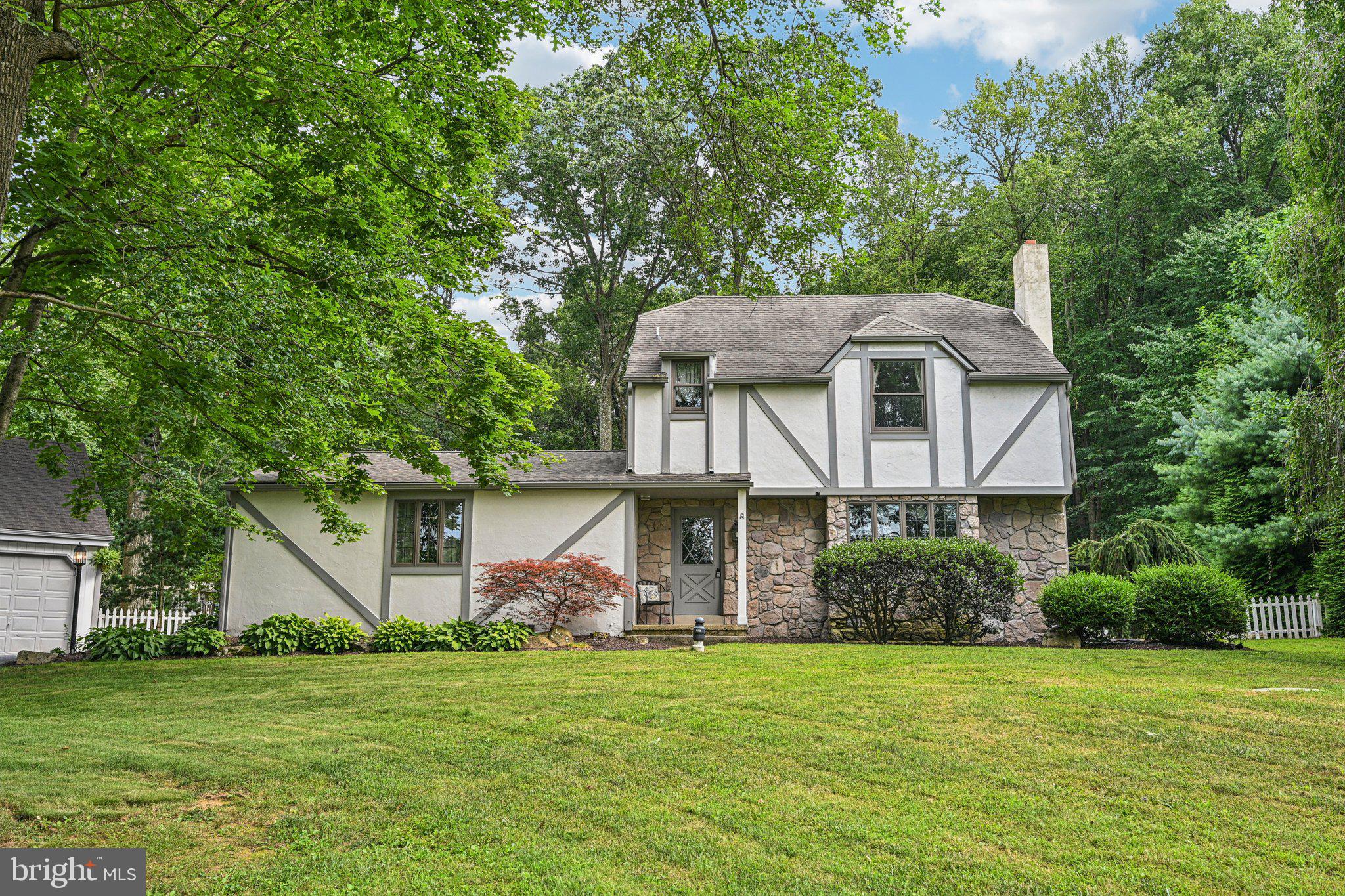 This charming Tudor-style home perfectly blends timeless character with thoughtful modern upgrades. Situated on a scenic, level 2-acre lot, the property offers peace and privacy while being just minutes from everyday conveniences. Featuring 4 bedrooms, 2.5 bathrooms, and over 2,400 square feet of living space, this home is both spacious and inviting. Step inside to a welcoming foyer, with the formal dining room to the right and stairs to the second floor straight ahead. The formal dining room boasts built-in shelving and a picturesque set of windows overlooking the front yard—ideal for intimate dinners or festive gatherings. The heart of the home is the fully remodeled kitchen, featuring classic white cabinetry, a beautiful blend of butcher block and quartzite and quartz countertops, and a mix of pendant and recessed lighting. The kitchen seamlessly flows into a spacious great room addition along the rear of the home, designed for entertaining or everyday family life. This sunlit space features a stunning stone fireplace, wood ceiling beam, and multiple windows and sliders that bring the outdoors in. Off the kitchen, a custom mudroom with built-in storage provides everyday convenience and connects to a cozy family room through elegant French doors. From the mudroom, you’ll also find access to a screened-in porch, patio, and the serene backyard—perfect for indoor-outdoor living. Tucked behind sliding barn doors is the private primary suite, featuring a walk-in closet and a beautifully designed en-suite bathroom. A well-placed powder room completes the main level. Upstairs, you’ll find three additional spacious bedrooms and a renovated center hall bathroom. The basement is partially finished, providing an ideal space for a playroom, media room, or bonus living area. There’s also a dedicated laundry area and abundance of additional storage space. The serene backyard is perfect for relaxing, gardening, or hosting outdoor gatherings. A detached oversized two-car garage is ideal for hobbyists or extra storage. Don’t miss your chance to own a one-of-a-kind property in a picturesque and convenient location—unpack your bags and move right in!