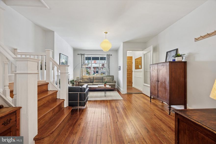 Magic is always in the details when an architect updates their own home, and this new-meets-old rowhome is no exception to that rule. It sits behind a front garden with mature landscaping including a Japanese maple and rose vine that climbs the stone porch wall. Inside, plenty of vintage charm and high ceilings meet refinished original pine floors throughout, while a combination of recessed lighting and just-so fixtures tie it all together with the contemporary Scandinavian-inspired kitchen. The vestibule entrance with original wainscoting, terracotta hex tile and glass door opens to the living room with front bay window, fireplace and turned staircase with detailed millwork. The warm and spacious dining room is open to the large kitchen, which has an expanded galley layout and an extra-large pantry closet. Not a detail was overlooked here: custom flat-front maple cabinets and drawers; veined quartz countertops; vertical subway backsplash with integrated Portuguese tiles; and large-format porcelain tile flooring are met with stainless steel appliances including a Samsung French-door fridge and five-burner range with convection oven and a Maytag dishwasher. Other thoughtful storage elements include open under-cabinet storage and a set of shelves recessed into the wall. Against the back wall, there’s a sweet window spot with a stylish pendant light for a breakfast table. And of course, a powder room tucked behind a pocket door was included in the first-floor upgrades. Upstairs the three rear bedrooms all flow into each other. The largest has two exposures, one from a window flanked by original mirrored closets. Both of the sunny middle rooms could easily serve as true bedrooms; one is currently used as a home office and would also make a great dressing room. The large front bedroom has a lovely bay window and an original glass-paneled door. All share a hall bath with original Victorian subway wall tile, functioning skylight and original cast iron tub. Back downstairs, basement access is behind a pocket door with an exposed brick wall along the staircase. This space is super functional as a playroom, home gym or maker space, thanks to the super-high-for-a-basement ceilings with plenty of LED lighting, and crisp painted cement floors and parged walls. Out the back door with a transom there’s a spacious deck with steps down to a good-sized L-shaped rear yard with a perennial herb garden surrounded by privacy fencing. The great location is just a couple blocks from the 3.2 acre Christy Rec Center, which has a pool and is currently undergoing major renovations and upgrades, and also convenient to Cobbs Creek Park for more greenspace. And Baltimore Ave shopping, dining and the trolley into Center City are just a couple blocks away.