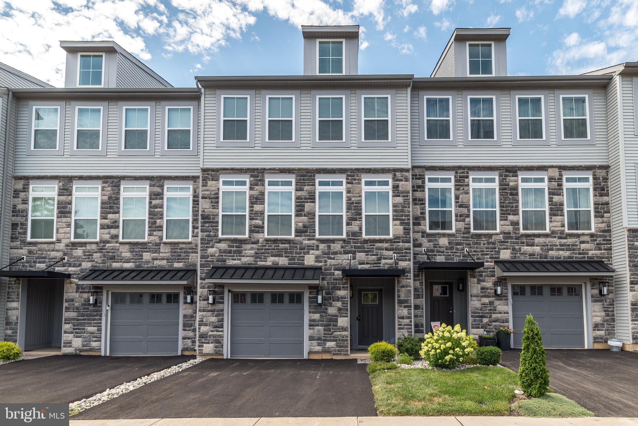 Welcome to this stunning Hamilton model custom townhome in The Fields at Constitution Square. This newer townhome offers a thoughtfully designed living space. From the moment you arrive, the natural-toned brice stone and siding façade makes a welcoming first impression. Step through the front door into a functional foyer with garage access, as well as entry to the finished lower level family room, a perfect flex space complete with large closet/storage area and sliders to walk out onto the professionally landscaped graystone patio with rock borders. Here you can relax and enjoy the manicured common grounds. The main level boasts an open-concept layout ideal for entertaining. The spacious living and dining areas are filled with natural light from oversized wall of windows and highlighted by luxury vinyl plank flooring and custom molding. The gourmet kitchen is a showstopper, featuring granite countertops, white shaker cabinetry, a stylish backsplash, stainless steel appliances, a four-seat island and large walk-in pantry. Sliders open to a maintenance free deck to enjoy and unwind. Additionally on this level is a half-bath. The upper level continues to impress with three generously sized bedrooms, and two full bathrooms. The luxurious primary suite offers a large bedroom, organized walk-in closet, and a spa-like en suite with dual vanity, glass-enclosed tiled shower, large linen closet and upgraded fixtures. One of the secondary bedrooms features dramatic two-level windows, while all share access to a spacious hall bath and an oversized linen closet. A large second-floor laundry room adds convenience. Additional highlights include freshly custom painted throughout, new blinds, new lighting, 2-car driveway and a garage equipped with a Tesla charger and room for storage. The community is nestled in a prime location along the Perkiomen Creek and just steps from the Perkasie Bike Path. Enjoy the ultimate in walkability with popular local favorites like Maize, The Perk, The Ram, Van Lieu's and Free Will Brewing all within a half mile as well as easy access to Route 309 and close proximity to Montgomery County, Philadelphia, and the Lehigh Valley. This home combines luxury, location, and lifestyle — all in one!