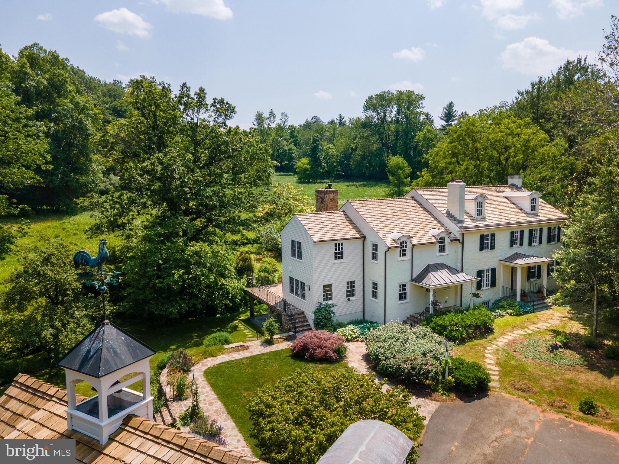 Welcome to Holly Springs, a delightful and private 14-acre sanctuary in the heart of Willistown Township. A winding drive and Allee of holly trees leads to the beautifully restored and expanded 4 bedroom 2 1/2 bath circa 1825 farm house, a detached two car garage with studio and 2 bedroom apartment on the second floor, and a 3-4 stall barn with work area, and hay loft. All the buildings, terraces and windows on the property overlook the spectacular grounds which are the result of a grand landscape master plan executed over the past 18 years creating and protecting a large meadow of native grasses and wildflowers, heritage hardwood trees, and the creation of gardens, bridges, woodland paths, and a small pond with gazebo. The majority of the property is enclosed with deer fencing and includes a gated entry with cattle guard.
The current owners purchased the property in 2005 and embarked on an extensive and ambitious restoration project adding a new two story addition to the house including a large open kitchen with breakfast and family rooms, a mud room and half bath on the first floor and large primary suite with sitting room and deck overlooking the meadow and gardens on the second floor. They worked closely with Warren Claytor Architects and Mark Slouf (builder), to ensure that the new addition met today's lifestyle needs while maintaining the charming and historic character of the house and property. Many of the materials were reclaimed or made to look original to the house; antique reclaimed hardwood floors, exposed beams and country cabinetry. The original part of the first floor includes the entrance hall which opens to the living room and dining room on either side, each with a fireplace, original floors and millwork. The dining room opens to the newer kitchen, family room, breakfast room, mudroom and powder room. A solarium was added off the front hall and can also be accessed from the family room; it takes full advantage of the southern exposure and offers stunning views. The original staircase in the entrance hall leads to the second floor which includes 3 original bedrooms and a hall bath and, the large, newer primary suite including, a dressing room, bath with vanity, tub and shower, large bedroom and sitting room and French doors leading to a deck overlooking the property. The attic is walk up, floored and offers great storage. The basement is full, unfinished and includes ample storage, a hot tub, outside entrance and what was the original “summer kitchen”, with fireplace and bake oven, and a springhouse, which continues to provide water for the home.
Holly Springs is named for the multiple springs flowing around the home and was initially part of the Brassey Tract that was purchased by Thomas Brassey from William Penn, and later divided into 3 tracts. The now 14 acre property is protected with a conservation easement through Willistown Conservation Trust and is surrounded by many other protected properties. There are equestrian opportunities on the property & easy access to trails.
Holly Springs is the quintessential country property allowing for total privacy and ideally located in the coveted Radnor Hunt area; yet minutes from the Main Line, West Chester; connections to all major roadways, the Philadelphia International Airport, Brandywine airport, R5 Rail Service, Amtrak and highly rated educational Institutions.