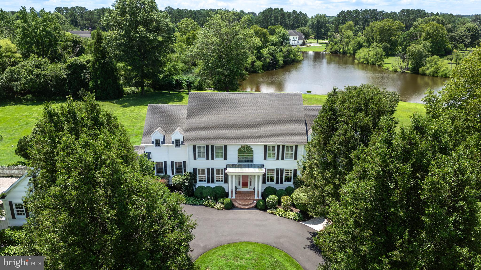 Welcome to this impeccably maintained and well appointed, five bedroom, approximate 5000 square foot, Colonial home with an interior that combines coastal character with elegant craftsmanship. Located in the sought-after Oxford corridor of Talbot County. This waterfront area invites a relaxed lifestyle with sunset strolls, golf cart rides to the country club, and bike trips to charming Oxford or Easton. Situated on approximately 5.17 acres, this private, estate-style property has a tree-line approach, a large freshwater pond and is surrounded by mature trees and perennial landscaping. Inside, enjoy a dramatic two-story great room with floor-to-ceiling windows showcasing the water views and the abundance of wildlife visitors. Exceptional millwork and rich cherry wood floors flow throughout the main level and center hall which lead to a gallery hall and sun-filled den. The first-floor primary suite includes a walk-in closet and newly remodeled bathroom with double vanities and French doors opening to the deck and pool. The chef’s kitchen features designer cabinetry, granite countertops, high-end stainless steel appliances, a central island breakfast bar and open separate dining area—perfect for everyday living or entertaining. Step outside through French doors to a new expansive Trex deck, ideal for all outdoor gatherings. The custom, gunite saltwater pool with dark plaster and travertine decking offers a secluded outdoor oasis.
Additional features include: High ceilings and oversized doors throughout • Extensive millwork and custom built-ins • 2x6 exterior construction • New HVAC • Fireplace with built-in bookcases in the great room • Spacious upstairs bedrooms with water views and Jack-and-Jill bathroom • Ample storage, including additional attic space above garage and third garage bay area • Landscaped yard perfect for gardening or relaxing in nature. Whether you’re seeking a full-time residence or weekend retreat, this exceptional property delivers elegance, craftsmanship, and unmatched amenities. Discover this ultimate Eastern Shore retreat.