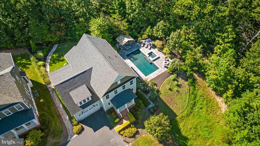 Some homes stop you the moment you pull in. This is one of them. Tucked at the end of a quiet pipestem on a rare cul-de-sac lot in Potomac Shores, one of Northern Virginia's most celebrated master-planned communities, this spectacular five-bedroom, five-bath home is enveloped by heavily wooded parkland. It delivers the kind of privacy and natural beauty that does not exist in standard subdivision settings. No rear neighbors. No visible rooftops. Just trees, birdsong, and a breathtaking backdrop that changes with every season. Step outside,e and the dream becomes real. A custom heated pebble-bottom pool anchors the backyard, flanked by a built-in waterfall hot tub, a beautiful hand laid slate hardscape  patio, and a wooden cabana, all framed by mature trees and lush landscaping within a fully fenced yard.
A private gate leads directly to Potomac Shores' community walking trails, making this a true haven for outdoor and nature lovers. It is the kind of outdoor living that makes guests go quiet. Inside, the home is as refined as its setting. Soaring ten-foot ceilings, rich dark hardwood floors, and craftsman details define every space. A quiet office with wooded views sets the tone for the entire home. The formal dining room and great room feature a dramatic wall of windows that frames the pool and wooded parkland like a living painting, no window coverings needed. The gourmet kitchen offers white cabinetry, granite countertops, double wall ovens, a cooktop range, a built-in microwave, and a large pantry. It opens seamlessly to the great room, so the cook is never out of the conversation. A sun-filled breakfast room overlooks the patio and yard, making every morning feel like a private retreat. The back foyer features a Pinterest-worthy arrival center complete with built-in cubbies, a bench, and hooks. Tucked privately behind the kitchen is a main-level suite with a beautiful full bath ideal for aging parents, guests, or an au pair. Upstairs, the primary suite is a true sanctuary: tray ceiling, hardwood floors, and a spa-worthy bath featuring a soaking tub, an oversized shower with river-rock-style flooring and floor-to-ceiling tile, and a private water closet and an absolute dream size closet. Three additional upper bedrooms, one has a private bath, and the other two share a dual-entry bath. The lower level features a custom wet bar with a beverage cooler and refrigerator, which anchors a generous recreation area perfect for game days or a quiet evening after a long day in the sun. A flex room,  full bath, and a large storage room with access to the rear yard round out this level. Potomac Shores is one of Prince William County's most sought-after addresses, offering a Jack Nicklaus Signature golf course, resort-style pools, a future VRE commuter rail station, and more than 800 acres of protected green space and trails. For buyers searching for a luxury home with privacy and a pool in Northern Virginia, this is the one that stands apart. This is not just a home. It is the life you have been picturing. The Potomac Shores Lifestyle HOA: $190/month — includes high-speed internet, trash,  resort pools, fitness center, multipurpose court, canoe launch, and full social calendar for residents. Ten miles of private walking trails. The Jack Nicklaus Signature Golf Course, Tidewater Grill, future Town Center, and the coming VRE commuter rail station on the Potomac River. Schedule your showing today.
