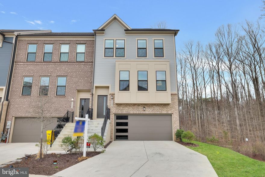 Welcome to this stunning end-unit townhome nestled in the heart of the highly sought-after Watershed community in Laurel, MD. With its striking contemporary vinyl and brick water table exterior, this home exudes curb appeal and charm from the very first glance. A two-car front-entry garage, extended driveway, and thoughtfully landscaped yard enhance its inviting presence, while the rear of the home opens to a fenced and private wooded backdrop—offering tranquility and unmatched privacy. Inside, a sun-drenched foyer greets you with wide-plank luxury vinyl flooring and custom-stained white oak stairs that lead to the main level. This open-concept living space boasts seamless LVP flooring throughout, freshly painted walls in a soft designer palette, and brand-new carpet on the upper level. Matte black hardware adds a modern, sophisticated touch throughout. The spacious family room is flooded with natural light from expansive windows, accented by automatic blinds and a sleek ceiling fan. Adjacent to the family room is a generously sized dining area—ideal for entertaining family and friends. The gourmet kitchen is a true showstopper, designed for both function and style. Outfitted with premium stainless steel appliances, 42” Snow White cabinetry, sleek quartz countertops, and a gas cooktop with a vented range hood, this space is perfect for culinary adventures. A deep stainless steel sink provides serene views into the forest, or you can enjoy privacy with the added window treatments. The oversized quartz island and large walk-in pantry offer ample storage, prep space and a convenient Skylight Calendar recessed against the wall. Just off the kitchen, a cozy sunroom leads to your private TREX deck—an ideal spot for grilling, relaxing, or gazing at the stars. Upstairs, the luxurious owner’s suite is a peaceful retreat featuring tray ceilings, elegant crown molding, a statement chandelier, and two spacious walk-in closets. Brand-new carpeting and soft, neutral tones provide a cozy ambiance. The spa-inspired en-suite bath includes double quartz vanities, a deep soaking tub, a frameless walk-in shower with floor-to-ceiling tile, and a private water closet—all accented with bold black fixtures. Two additional bedrooms are filled with natural light and include new carpet, ceiling fans, and window treatments. A secondary full bathroom with tiled tub/shower combo and black finishes, along with a laundry room and linen closet, complete the upper level. The fully finished walk-out lower level features a spacious recreation area that opens to a beautifully landscaped and privately fenced backyard—ideal for entertaining or quiet moments in nature. A fourth bedroom with an en-suite full bath, new carpet, and ceiling fan is perfect for guests, a home office, or multi-generational living. The oversized front-loading garage with a convenient EV charging outlet adds functionality while preserving backyard space and natural views. Built with an emphasis on energy efficiency and quality, this home includes a 92% efficient gas heating system, high-efficiency HVAC, Tyvek HomeWrap, dual-pane Low-E windows, premium insulation, a sealed air barrier, insulated ductwork, a steel garage door, tankless water heater and durable 35-year architectural roof shingles. Perfectly positioned for effortless commuting, this home is minutes from major highways, BWI Airport, NSA, and Fort Meade. Located in the vibrant Watershed community, residents enjoy resort-style amenities including a clubhouse, swimming pool, dog parks, walking trails, playgrounds, picnic areas, and green spaces. Enjoy proximity to top-tier shopping and entertainment at Arundel Mills Mall and Maryland Live! Casino. Watershed offers the perfect blend of convenience, community, and nature—providing a lifestyle that’s as vibrant as it is peaceful.