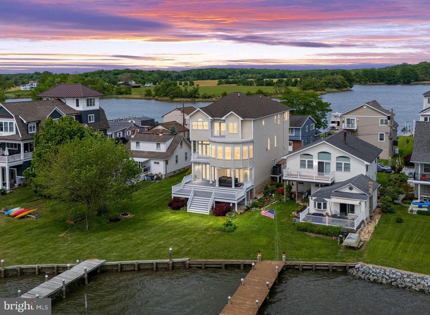 SPECTACULAR! This Carolina Coastal-inspired waterfront home sits on a peaceful peninsula with panoramic Chesapeake Bay views — delivering the waterfront lifestyle most can only dream of.

With nearly 4,700 sq ft of light-filled luxury, soaring ceilings, and walls of windows, you’ll soak in every sunrise and sunset. The gourmet chef’s kitchen features a french door style professional fridge/freezer, double ovens, warming drawer, island, built-in banquette, and walk-in pantry. Beyond the elegant dining room you’ll discover a grand living space with stunning water views and gorgeous maple floors throughout.

Upstairs, the primary suite is the perfect getaway, complete with a spa-like bath, expansive custom walk-in dressing room, vaulted ceilings, and a private Juliette balcony where you can watch the Great Blue Herons, Ospreys, and Bald Eagles soaring over the creek. Enjoy your morning coffee while watching the sunrise in the enclosed sunroom.

The lower level is designed for effortless entertaining, with a bright rec room with double french doors, wet bar with custom oak bar top. Enjoy cozy movie nights in the theater room with lighted tray ceilings (or convert to extra BR). Laundry hook-ups available for true first floor in-law suite potential.

Additional highlights include a library with rolling ladder, pocket doors and balcony, elevator with whimsical touches, loft/office space, oversized garage with epoxy-coated floors and carriage style doors. For your peace of mind, sellers installed brand-new high efficiency Trane HVAC systems, water heater 2yrs new, new Duradek balconies, hurricane rated shingles, hurricane straps on roof trusses. Minimal risk flood ins only $474 year. Huge clean and lighted storage space with concrete floors under the main level. Every detail of this home has been thoughtfully designed and executed.

Outside, the beautifully landscaped yard leads to your private pier, perfect for boating, kayaking, paddle boarding, crabbing or fishing. Or simply relax on the multi-level deck where you can savor the salty breeze from the hot tub.

Tucked in a well established neighborhood that is rich with local history, near 1300 acre North Point State Park and Fort Howard Park, you’ll feel worlds away while staying close to Baltimore, Annapolis, and DC. Boaters will appreciate easy access to top destinations on the Bay.

This is more than just a home — this is a once-in-a-lifetime opportunity to claim a slice of waterfront paradise. Mark Twain said it best. EXPLORE. DREAM. DISCOVER. Come experience coastal small-town living at its absolute finest. Schedule your private showing and make this one-of-a-kind Chesapeake Bay retreat your own!