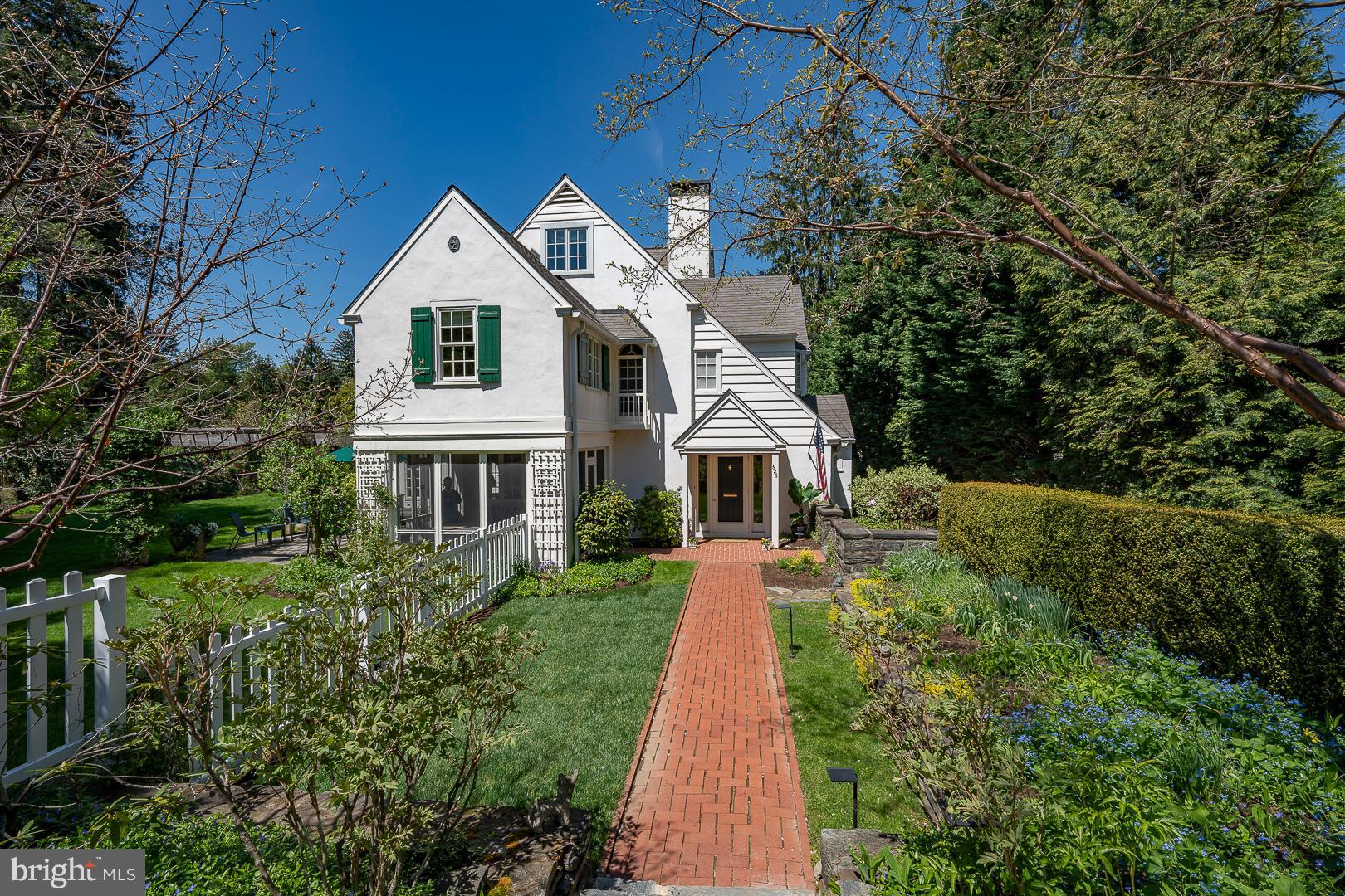626 Winsford Road in northside Bryn Mawr is located on a quiet cul-de-sac, the private road portion of Winsford. This is a walk to location for all of Bryn Mawr, including the SEPTA rail station (with express service to Philadelphia), stores, the movie theatre and reataurants. The cherished and leafy neighborhood location of this property enjoys no through traffic, sidewalks and beautiful and prominent surrounding houses, each with their own distinct character. Moments on foot to the oasis campuses of both Bryn Mawr College and Baldwin School.
The house is an elegant 1920's original Cotswold style home with stunning but understated landscaping that has been tastefully and extensively renovated to include all modern amenities and improvements. A screened-in porch provides cover for April-October enjoyment out-of-doors. Outdoor patio spaces truly become private outdoor 'rooms', with extensive stone and flag masonry stonework, a pergola and terraced gardens, a passionate gardener's delight. The house opens and flows elegantly from the kitchen, the dining room, the living room and the foyer to all of these special outdoor spaces, with thoughtful and creative architecture, both old and new.
This is a five bedroom, three and one half bath, three story house with an attached garage, a stone hearth log fireplace, beautiful formal reception rooms, and a progressive, open floor plan. It features a hideaway library and a cozy family room adjacent and just up from the modern granite, eat-in kitchen with soaring, beamed ceilings, heated tile floors, custom cherry cabinets, a granite island with bar sink and double atrium doors out to the garden.
Approach the house from four stone steps, down to a brick walkway to the front vestibule. Front door opens to an elegant foyer, with coat closet and powder room discreetly tucked aside, and hardwood floors throughout. Foyer flows to formal living with stone fireplace and door to screened in porch. Living room had a large bay window which brings great light into the space. Living room has passageway to hideaway library, and on the other side, opens graciously to the formal, vaulted dining room. Dining room opens out to side patio with double atrium doors, and flows into kitchen. Rear transverse hall from kitchen has several stairs up to family room, with barrel vaulted ceiling and beautiful replacement windows on all three sides. Hall continues to a spacious mud room with ample closets, back door and laundry room, which includes a chute and utility sink.
Second floor has landing with exquisite, radial arched twin panel doors. Owners' bedroom suite has Juilette balcony, custom twin bowl marble vanity bath with a walk-in stall shower, owners'retreat room and walk-in closet. Two generous family bedrooms, each with closets and replacement windows share a second full bathroom. Third floor has two additional family bedrooms which share a third, full hall bathroom.
Lower level has finished portion for second family room or studio, with utility sink. Wine cellar has temperature and humidity controls. Storage and mechanical work room has door to outside stairs. Attached, one bay garage and tool shed.