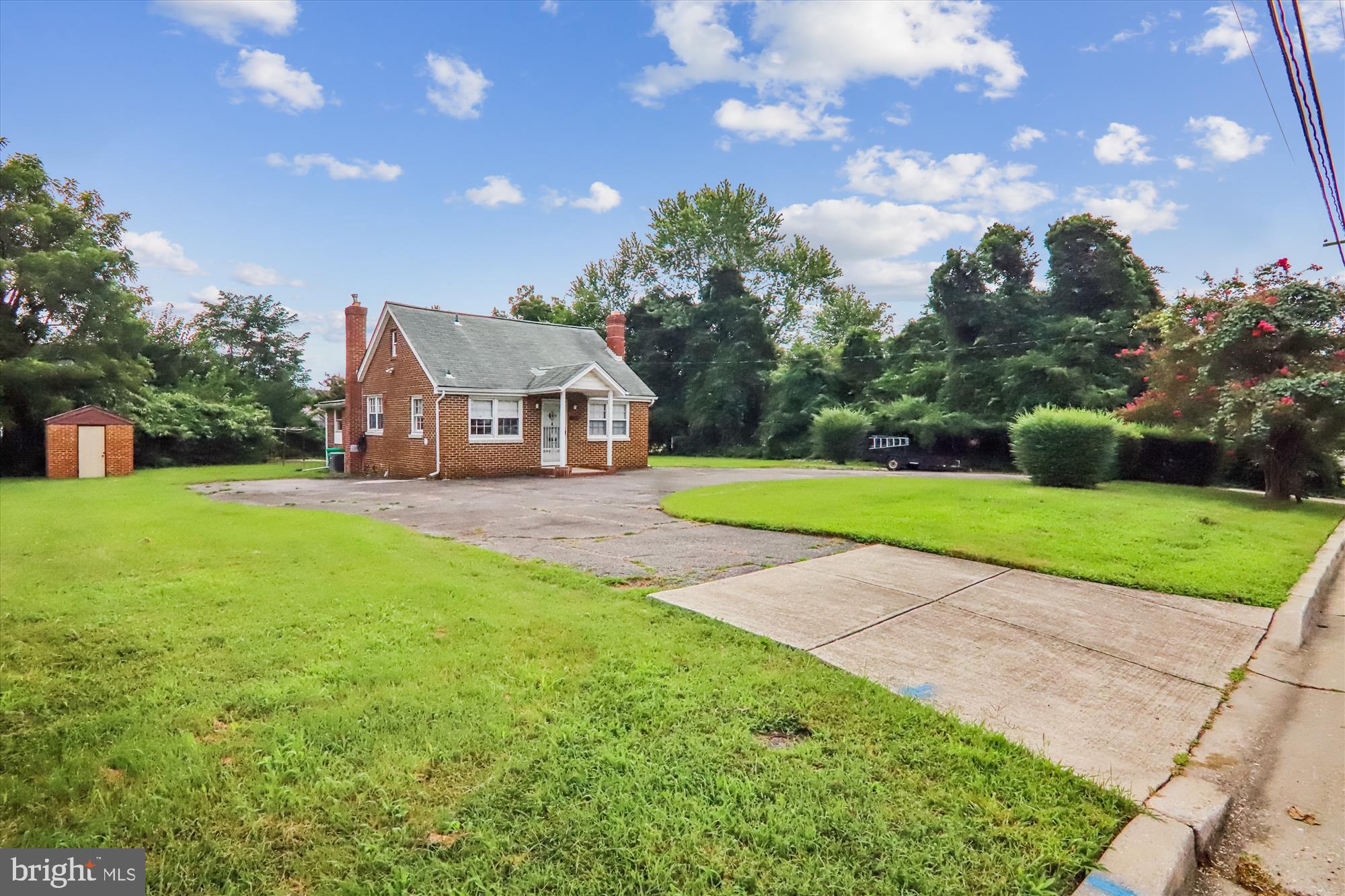 Welcome to 7001 Presley Road, a solidly built and well-maintained Cape Cod located just 0.7 miles from the Seabrook MARC Train Station. Nestled in a quiet suburban neighborhood, this home offers convenient access to Downtown D.C., NASA Goddard, and Luminis Health Doctors Community Medical Center.
Set on a picturesque 25,077-square-foot lot (0.5760 acre), the property greets you with an expansive U-shaped driveway that provides ample parking and a covered front entry.
Inside, the living room features a wood-burning fireplace, while the bright table-space kitchen includes vinyl flooring, wood cabinetry, and an encased refrigerator. Beyond the kitchen is a bonus room with vinyl plank flooring accented with exposed brick with access to the back yard.
The main level offers two spacious bedrooms plus another large room that the owners previously used as an additional bedroom. There is also a versatile family room with access to the side yard. There are two bathrooms, one includes a main level laundry room.
Upstairs features a large, finished attic with eave storage and an attached half bath.
The basement features two separate, large storage areas, a French drain system with a sump pump - providing waterproofing with a lifetime guarantee. The basement is accessible via an outside door topped with a small awning.
Outdoors, the property features a large, level, lush yard, a rear patio, and a brick shed. The location is only minutes from Presley Manor Park and provides quick access to I-495 and the Baltimore-Washington Parkway.