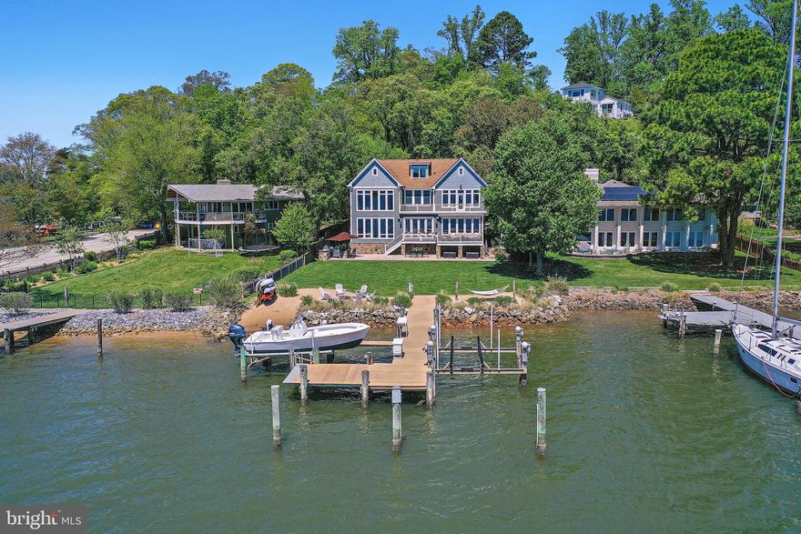 This coastal waterfront home offers a rare combination in the Annapolis area: deep water, wide 10+ mile views, and a flat, level lot that makes enjoying the outdoors effortless. Located just minutes from downtown Annapolis by car or boat, it’s perfectly positioned for both everyday living and weekend entertaining.
Spend your days outside—whether relaxing on the deck, gathering around the stone firepit, cooking in the outdoor kitchen, or heading out from your private 75' pier with two lifts and over 10 feet of water depth. The backyard flows easily to the water, making it ideal for hosting or just enjoying a quiet sunset by the shore.
Inside, the home is filled with natural light and designed for comfort and function. The main level offers open living spaces with expansive water views, a well-equipped chef’s kitchen, and a custom bar for easy entertaining. Upstairs, the primary suite feels like a private retreat with floor-to-ceiling windows, hidden electronic shades, and a spa-style bath built for two.
With four bedroom suites, bonus spaces for work or fitness, and thoughtful details throughout, this is a home built for easy waterfront living in one of Annapolis’ most sought-after neighborhoods.