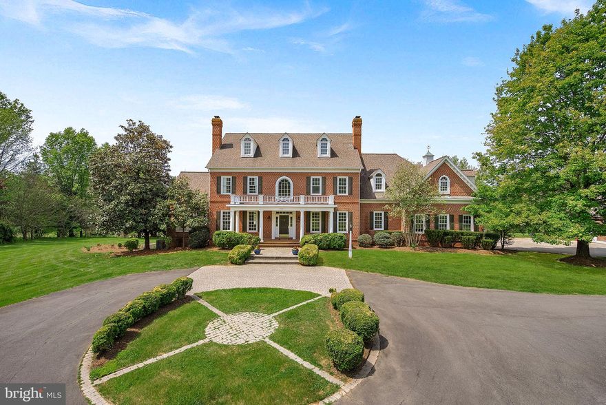 Built by Weatherburne, this stately Jamestown model custom Colonial is privately situated on 5.79 acres just minutes from Leesburg, offering a rare combination of luxury, space, and convenience with easy access to the Dulles Corridor, Washington Dulles International Airport, and Washington. Encompassing over 9,000+ square feet of living space, this exceptional property has been thoughtfully maintained with major improvements, including a renovated kitchen and new roof in 2018, along with a new four-zone HVAC system installed in 2024.
Designed with both comfort and functionality in mind, the home offers an impressive layout filled with generously sized living spaces, timeless architectural details, and quality craftsmanship throughout. Three stately wood-burning fireplaces create warm and inviting gathering spaces while adding to the home’s classic elegance and character. The beautifully renovated kitchen serves as the heart of the home and features timeless finishes, a bay window breakfast area overlooking the private backyard, a butler’s pantry, and a conveniently located washer and dryer just off the kitchen. The inviting family room showcases custom built-ins and ample gathering space, while the expansive sunroom fills with natural light and provides the perfect setting for relaxing or entertaining. A formal dining room and dedicated office complete the thoughtfully designed main level.
The bedroom level offers exceptional flexibility with spacious secondary bedrooms, including two bedrooms connected by a Jack and Jill bathroom, another bedroom with an ensuite bathroom and convenient laundry chute, and an additional room previously used as a school room that could easily function as another bedroom, office, playroom, or flex space. The expansive primary suite serves as a luxurious retreat featuring heated floors in the primary bathroom, an extensive closet, and a private sitting room perfect for relaxing and unwinding.
Additional finished living space continues throughout the home, including a private upper-level bedroom suite complete with a full bathroom and cedar closet chests ideal for guests or multigenerational living. The fully finished walkout lower level offers incredible versatility with a spacious family room opening directly to the backyard, a full guest bedroom and bathroom with heated floors, two large storage rooms, and a soundproof room ideal for a movie theater, gym, music studio, or private retreat.
Outdoor living is equally impressive with sweeping views, a spacious deck with a gazebo, and a large patio that doubles as a sports court, perfect for entertaining or recreation. A separate carriage house offers finishable space and two garage bays, creating endless possibilities for hobbies, storage, guest accommodations, or future expansion, completing this truly exceptional estate property. Combining timeless architecture, expansive living spaces, and an unmatched location, this extraordinary estate offers a rare opportunity to enjoy refined country living just moments from town conveniences and major commuter routes.