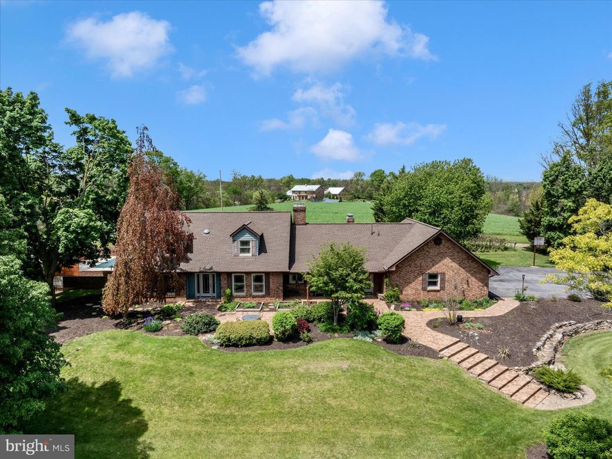 Seller requests no showings  before 4:30 p.m. Welcome to this exceptional custom-built county home on over 5.5 private acres in beautiful Smithsburg, Maryland.  This 1983-built residence offers approximately 2,925 square feet above grade of timeless charm and impressive quality throughout, featuring a handmade brick exterior with matching brick paths and fencing.
Step inside to discover a desirable main level primary bedroom suite with door that leads directly to the inground pool, beautiful hardwood floors, extensive trim, and solid wood doors. The spacious kitchen boasts custom cabinetry, while a large main-level office provides convenient workspace. The bright four-season sunroom opens directly to the patio and sparkling in-ground pool—perfect for entertaining or relaxing year-round. Additional highlights include a family room with cozy brick fireplace, oversized 2-car garage, and all vinyl replacement windows for energy efficiency. The home also features 2x6 exterior walls, a brand-new architectural shingle roof, a new heat pump, and an 80-gallon hot water heater, along with a radon remediation system, water softener with UV light, and a main-level half bath that is fully plumbed and ready for conversion to a full bath with shower and tub. The basement offers a Vermont Casting wood stove and a large hobby room.
Situated on over 5.5 acres with potential to subdivide (buyer to verify), this special property also offers an assumable 2.25% loan—a rare opportunity in today’s market!
Don’t miss this unique home that perfectly blends classic craftsmanship with modern updates and fantastic outdoor living space.