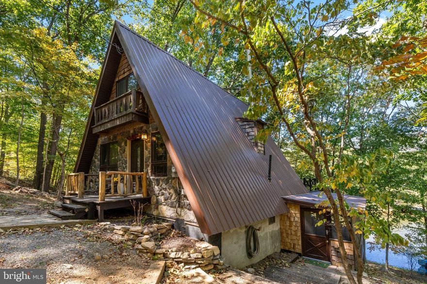 Welcome to 302 Tuscarora Trail, a charming A-frame tucked away on 1.18 acres of lakefront property. This home has views of both the water and surrounding mountains, giving you a peaceful retreat to enjoy year-round. Spend your mornings on the screened-in porch, or gather around the fireplace on cool evenings. A ductless mini-split provides comfort in every season, making this a great option for either a weekend getaway or a full-time residence. Located just 15 minutes from downtown Berkeley Springs—while still enjoying the quiet and beauty of lakeside living.