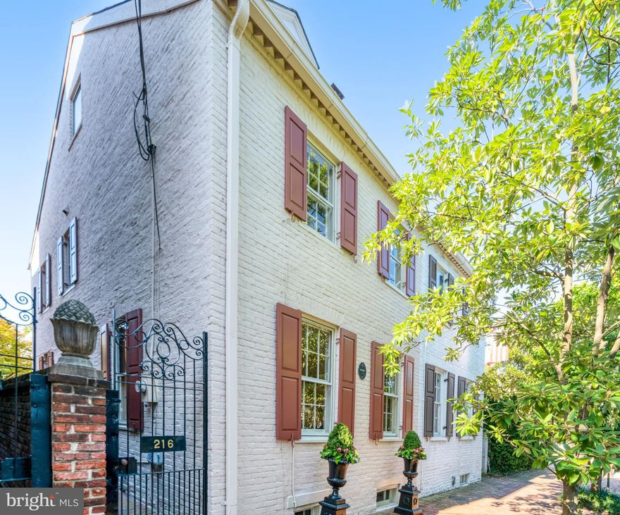 216 Wolfe Street is a distinguished residence in the heart of Old Town Alexandria’s historic Southeast quadrant. Dating to circa 1800, this exceptional property combines historic character with modern comfort, offering 2,545 square feet of space with four bedrooms and two and a half baths. A formal entry hall sets the stage for the home’s timeless elegance, with original hardwood floors spanning both the main and upper levels, complemented by much of the home’s preserved woodwork. The main level features a gracious living room with a wood-burning fireplace, a formal dining room with its own fireplace, and a bright eat-in kitchen with gas cooking. French doors open from the kitchen to the garden, extending the living space outdoors. The private garden is a highlight of the property, offering a brick patio, generous planting beds, and gated alley access. A unique side entrance enhances the sense of privacy, while a powder room and coat closet provide convenience on the main level. Upstairs, the primary suite includes a fireplace and en suite bath, creating a serene retreat. Two additional bedrooms and a hall bath complete this level. The top floor offers the home’s fourth bedroom—a versatile space equally well-suited for guests, a home office, or a studio. The expansive basement, accessible from within the home, provides substantial storage and the opportunity for future expansion. Set along one of Old Town’s most storied streets, 216 Wolfe Street presents a rare opportunity to own a residence of historic significance with enduring architectural details—perfectly suited for modern living in an unparalleled location.