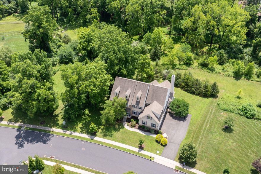 Welcome to Whispering Pines, an esteemed community situated within the highly regarded Southern Lehigh School District. This Cambridge Country Manor residence is set on 1.5 acres of tranquil grounds, offering approximately 5,800 square feet of well-appointed living space, including a finished walk-out basement with daylight windows.
Upon entry, guests are greeted by a spacious foyer featuring elegant hardwood flooring that extends into the adjacent formal dining area. Opposite the foyer lies a refined formal living room. The expansive chef’s kitchen boasts recessed lighting, stunning granite countertops, a central island with pendant lighting, gas range, double ovens, and a butler’s pantry. The open floor plan seamlessly connects to the great room, distinguished by a cathedral ceiling, a wall of windows, and a gas fireplace. Adjacent is the breakfast room, also with a cathedral ceiling and sliding doors leading to a private deck—an ideal setting for enjoying morning coffee or evening refreshments in a serene atmosphere. The main level further includes a study/bedroom, two powder rooms, access to a three-car garage, and a secondary back staircase.
Ascending the main staircase, double doors open to the primary bedroom suite, which features a tray ceiling, a 16’ x 10’ walk-in closet, and a luxurious spa-inspired bathroom complete with a soaking tub, a shower outfitted with floor-to-ceiling tile, a built-in bench, and a glass enclosure. Nearby, a second primary bathroom offers a bubble soaking tub and a tiled shower with a bench and glass enclosure. Three additional bedrooms are located on this level: one en suite with a shower-tub combination and double sink, and two others sharing a Jack and Jill bathroom. A conveniently located laundry room with a sink is found at the end of the hallway on the second floor.
The finished walk-out lower level provides extensive additional living space, perfectly suited for recreation, a theater/media room, hobbies, fitness, and wellness pursuits. Ample storage is available in the unfinished portion. Sliding doors open to a paver patio, presenting a peaceful setting surrounded by lush greenery and calming natural views.
This property enjoys a prime location with easy access to dining and shopping, including The Promenade Shoppes, area golf courses such as Saucon Valley Country Club, leading medical facilities including St. Luke's and Lehigh Valley Hospital, and entertainment venues like Bethlehem’s SteelStacks. Major highways (I-78, 309, 378, Northeast Extension) and Lehigh Valley International Airport are only a short drive away.