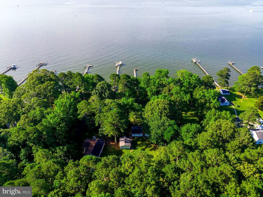 RARE WATERFRONT!  Enjoy the expansive views near the mouth Patuxent River and you are literally one minute by boat to the the Chesapeake Bay!  Set your chairs on the L pier and watch the sunrise over the water. You can also see Solomons Island from the dock.   Take a 5 minute boat ride  for dinner at any of the waterfront restaurants.  Live the waterfront lifestyle with crabbing and fishing on the 190' +- pier or hanging out on your own  beach.  76+- waterfrontage has a bulkhead, protecting from any erosion.  Beautiful mature trees provide the perfect shade for naps in your hammock.  

The owner has a valid sanitation permit for a new septic in hand.  This home  is being sold in as-is condition.  The price reflects condition of home. Needs to be Cash offers.