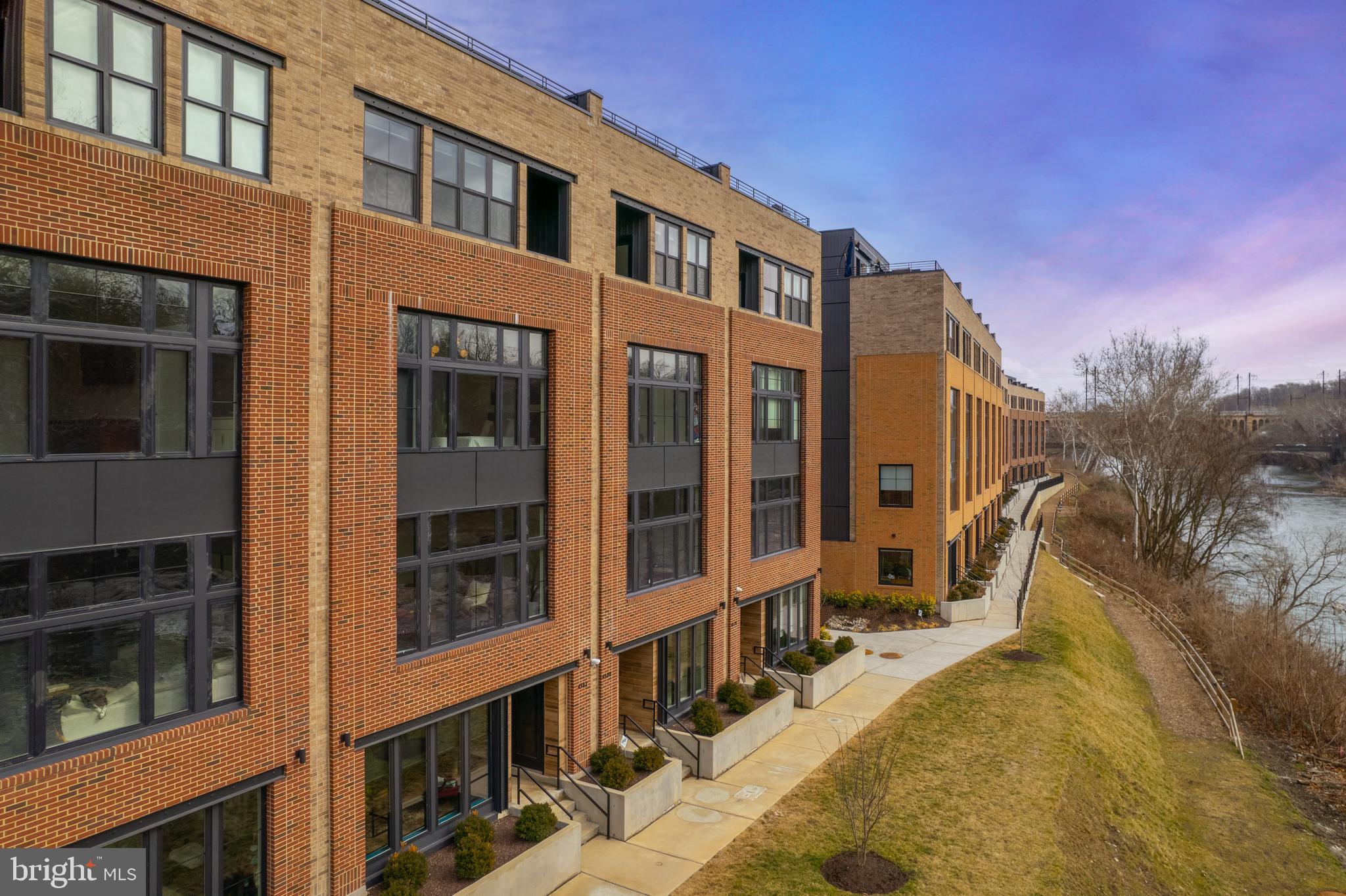 Stroll to dinner on Main Street, walk the historic Manayunk Canal Path, take the nearby train into the city, or catch a gorgeous sunset from your roof deck at this impeccable newly constructed townhome in the riverside community of Locks in Manayunk. Decked out with every high-end luxury upgrade you could wish for, this 4 bedroom, 3.5 bath house comes complete with a Savant home automation system, Lutron controlled lighting and shades, 4K ultra-HD projector for cozy, at-home movie nights, 5-stop elevator and a sound system. The ground floor offers a sunlit study with custom built-ins and beautiful views of the Schuylkill River, and an oversized 2-car garage. As soon as you enter the main floor you are immediately struck by the exquisite finishes, the floor to ceiling windows allowing for incredible natural light and a functional, open floor plan, perfect for everyday living or entertaining family and friends. The gourmet kitchen will delight the home chef, with custom shaker cabinets, Wolf 6-burner range, Sub-Zero refrigerator, large center island with quartzite counters, pantry, spacious dining area and breakfast area with custom built-ins and beverage refrigerator. The living area features beautiful views of the river, with an ultra-HD theater-quality projector and screen, and high-end Lutron UV blocking shades that lower at the touch of a button. The third floor features a large bedroom overlooking the water, with dual closets and full bath with walk-in shower. An additional two bedrooms, one being used as an office, a full hall bath and convenient laundry room complete this level. The fourth floor serves as the luxe owner’s retreat, with primary bedroom with Lutron blackout shades, large walk-in closet, additional 2 closets, and a private balcony with river views that will become your ultimate morning coffee spot. The expansive primary bath features dual vanities, walk-in marble shower and large soaking tub. Relax in the adjacent sitting room, or make morning coffee at the convenient beverage center. Topping off this fabulous home is the roof deck, with Ipe wood decking, built-in lighting and sound system, showcasing expansive, sunset views of the Schuylkill River and Manayunk. All this and 7 years remaining on the Tax Abatement! Set in an ultra-convenient location, just blocks from Main Street, the Schuylkill River Trail, the Manayunk train station and 76.