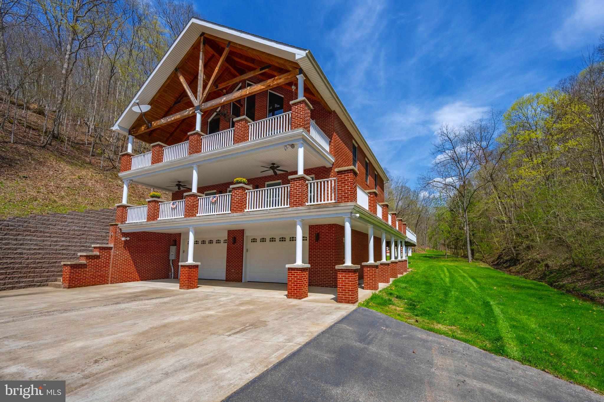 "Remarkable Route 5 Home" situated on 250 +/- ACRES! Where solitude meets convenience, just 7 +/- miles from I-79 in the heart of the Appalachian Mountains of West Virginia. Through the private gate, the paved driveway leads through a beautiful meadow as mature hardwood trees surround the property on the ridges above. Pass by the renovated, rustic barn and chicken coop to this elegant 6,000 +/- sqft custom inside & out brick home featuring exposed beams and vaulted ceiling, hardwood cherry floors, open floor plan, expansive living room and upstairs bedroom with private deck, brand new kitchen and pantry, wood burning & gas fireplaces, workout room, and so much more. (See attached list of upgrades). Take in the sights & sounds of the spring fed creek that runs beside the home, viewing abundant wildlife in the plush green yard, or enjoy your favorite beverage on the wraparound multi - level deck with integrated hot tub! Total seclusion as internal trails meander the property through creek bottoms & ridge tops perfect for hiking, biking, & ATV riding. The home is handicap modified with its own lift and strategically placed ramps providing adequate access. The 2 stall integrated garage provides ample space for vehicles and storage plus the detached 2 stall, heated garage allows for tractors & toys. Come see this beautiful property in Almost Heaven today! 20 +/- miles to Flatwoods, 25 +/- miles to Stonewall Jackson Memorial Hospital, 8 +/- miles to Burnsville Lake WMA, 80 miles to Morgantown, 80 miles to Charleston, WV.