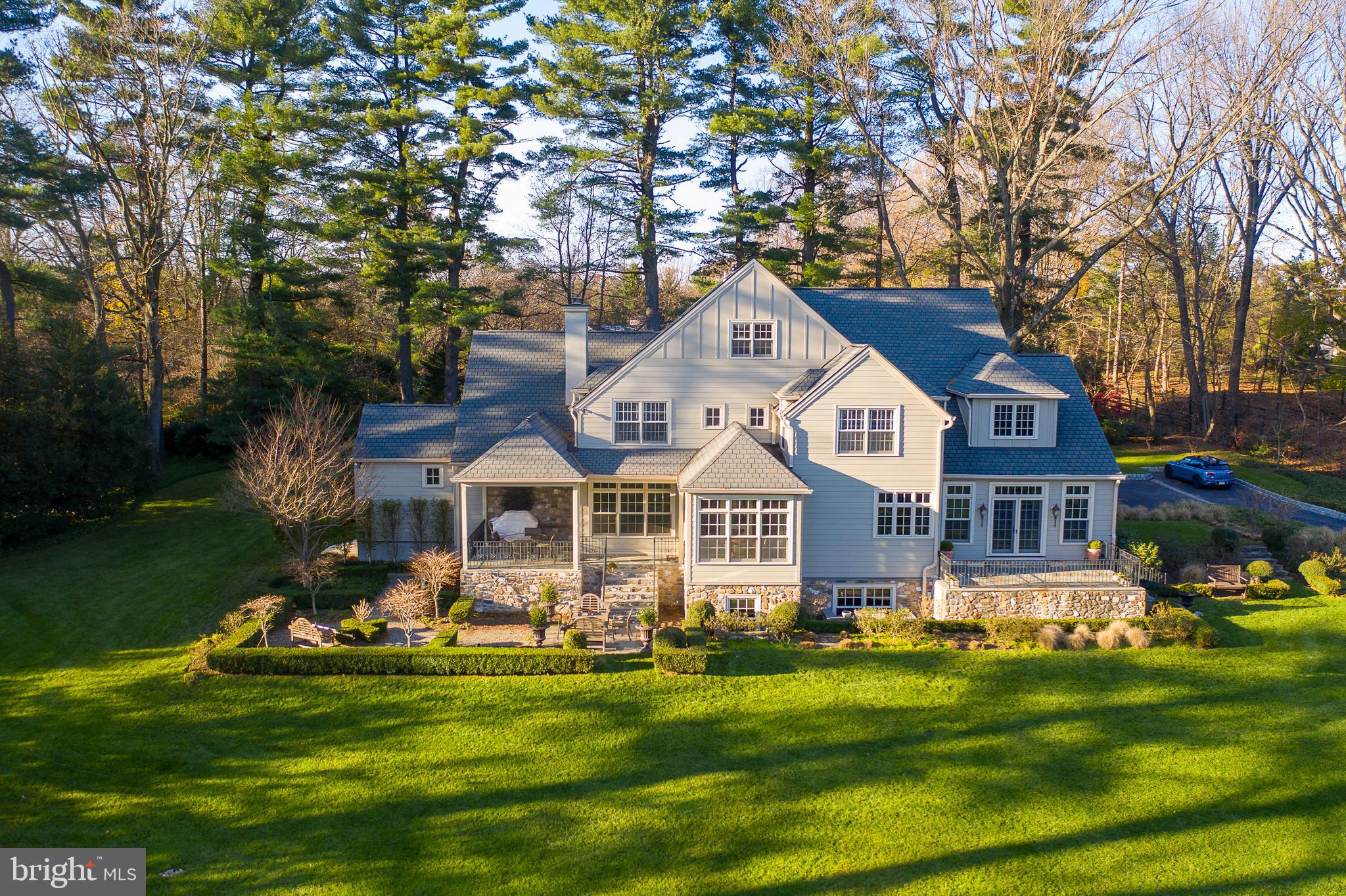 Walkable to the historic village of Gladwyne yet presenting as if you are miles away from everything, find this handsome Modern Farm house on a truly secluded 1.45-acre park-like parcel. Built in 2005 with the architectural emphasis being as many windows as possible, this 5-bedroom, 4-full bath main home captures every bit of natural light and is further enhanced by views of a broad, flat lawn, irrigated gardens and the glimpse of the property’s 2-bedroom guest cottage/party barn. A center foyer floor plan in the main house is enlivened by high ceilings and warm-toned hardwood floors though out the main level. The living room features a bespoke fireplace, and a large dining room with French door leads to a raised terrace that offers uninterrupted transitions from indoor to outdoor entertaining. An open kitchen and family room with custom shelving and wood burning fireplace are adjacent to a breakfast room overlooking an inviting covered terrace surrounded by gardens and ringed by evergreens for privacy. The master suite, found on this first level, offers a deluxe, resort quality bath, detailed in inviting neutrals with two spacious walk-in closets. Access to a private walled garden makes the suite a true retreat space. Ascend to the second level from either the more formal front turned staircase or the rear stairs to find 4 bedrooms and a large office connected by a wide hall with high ceilings. Brightened by large windows, the fully finished lower level offers well designed space for recreation with television area, billiard and ping-pong space, temperature-controlled wine cellar, full bath and tremendous storage. A few steps from the main house is the most charming 2 bedroom guest cottage. A stone terrace surrounded by a hedge for privacy opens to a large party venue with vaulted ceiling adjacent full bath, kitchenette, laundry area and storage. The second level offers two bedrooms, a full bath with tub/shower, and a full kitchen. Wide planked floors add charm while a large painted brick fireplace brings warmth and focus to the Living Room wall… Exceptional location, home, property and amenities. An engaging blend of charm and chic styling Main house square footage 7993 + finished lower level and 2132 square feet in the adjacent carriage house...carriage home built in 1950 ...main residence in 2005