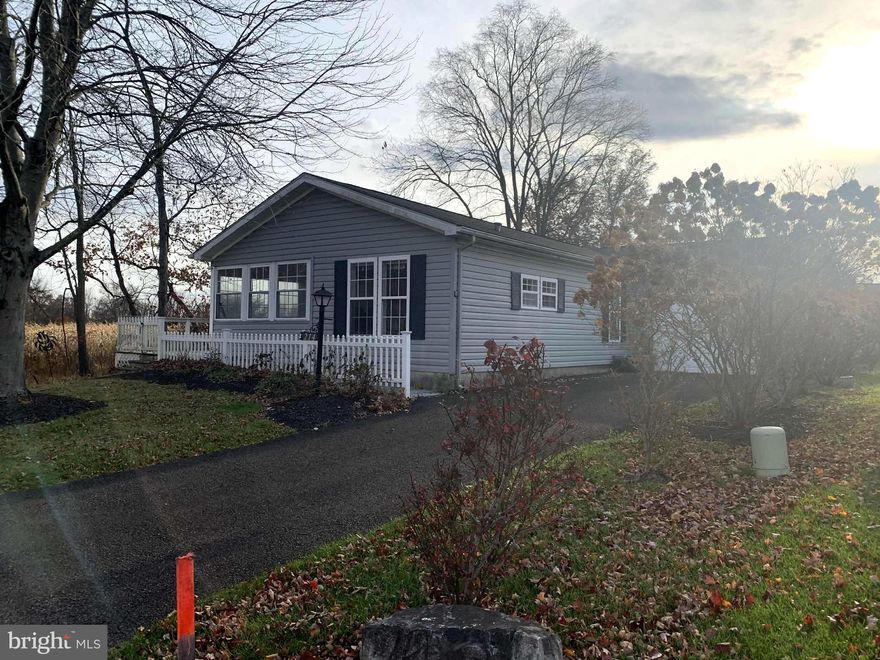 The  ONE you have been waiting for!! Located at the end of the charming peaceful street, overlooking the beautiful farmland and partial woods! The location is fabulous for the buyer who needs to feel some space. 
The long extra driveway with room for 3 cars is  a real plus! Garage opens to the laundry room/mud room for convenience. Incredible landscaping with magnificent hydrangeas affords pleasing long-lasting color in all seasons.  The back and  side garden area has the most beautiful King Alfred daffodils and other sweet perennials lining the edge of the property. Such a nice surprise of color every Spring! It needs some loving and maintenance to bring it back to perfection.
The entrance has been modified with a charming fenced ramp in the front from the driveway to the deck on the back of the house. Instead of the open porch on this model, Seller has installed an enclosed porch with a slider door which serves as the "front door". This opens to a sunroom and affords  2 sided views of the countryside farmland. There is another slider to the kitchen as well as another door to the living room. 
The entire house has beautiful laminate floors and tiled in the bathrooms. The kitchen has higher end stainless steel appliances ( Frigidaire Cooktop stove, Fisher and Paykel double drawer dishwasher, oversized deep sink for those big roasting pans and cookie sheets, and neutral upgraded Carrera marble counters and tile backsplash. Sweet end of the room breakfast area has that great farm view to enjoy with your morning coffee! Dining room has double window overlooking the same, and is open to the bright living room with custom-sized wall of bookcases ( not attached). Down the hallway to the laundry room with newer front-loader washer and dryer on their pedestals, and exit door to the garage.
Main Bedroom has deep walk-in closet, and double-door to main bath, which has been updated with marble-top cabinets and lots of storage in the vanity and really deep linen closet, walled commode, and large updated shower with built-in seat. 2nd bedroom has more farm view and spacious closet space.
House needs loving and cleaning and will be totally sold AS-IS. Buyer will be assuming responsibility for the McKee Group pre-inspection issues when that list is available. Buyer must be willing to accept the "diamond-in-the-rough" situation, but knowing that what was once improved, was well-done originally.