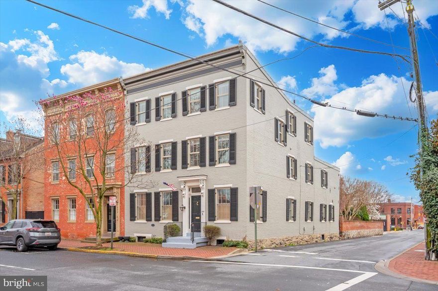 Circa 1880, this downtown Frederick home carries the kind of character you simply can’t recreate. Set right on Church Street—one of the most recognizable and loved streets in the city—this six-bedroom property blends historic detail with the right modern updates in a way that actually feels natural, not forced. Inside, the home immediately shows off what makes these properties so special. Original solid hardwood floors run throughout, paired with exposed brick and timber that have been preserved rather than covered up. There’s a sense of depth and texture here that newer homes just don’t have. Every room feels intentional, with just the right balance of old and new. The kitchen has been completely redone with a clean, high-end finish, designed for someone who enjoys cooking and entertaining. It opens comfortably into the main living areas, making the flow of the home feel easy and connected without losing the defined spaces that give older homes their charm. With six true bedrooms, there’s a lot of flexibility here—whether you need space for guests, offices, or just room to spread out. Each level has its own full bathroom, which makes day-to-day living simple and practical, especially for a home of this size. Out back, the courtyard feels like a true extension of the home. Surrounded by exposed brick walls, the space is both private and full of character, with thoughtful landscaping that brings it to life throughout the year. In the spring and summer, it naturally fills in with color and greenery, creating a setting that feels tucked away and quiet despite being right in the middle of downtown. Whether you’re hosting friends or just stepping outside for a few minutes, it’s a space that is timeless in its beauty. One of the standout features is the outdoor space above ground level. The primary bedroom includes its own private balcony, while the third-floor balcony offers a view that’s hard to come by—looking out over the steeples of downtown Frederick. It’s a subtle reminder of exactly where you are, and why people love being here. All of this sits just steps from everything downtown Frederick has to offer—restaurants, shops, coffee, and the overall energy that makes this area so desirable. Homes like this don’t come around often, especially ones that have been updated in a way that still respects what they are. This is one you feel the moment you walk in.