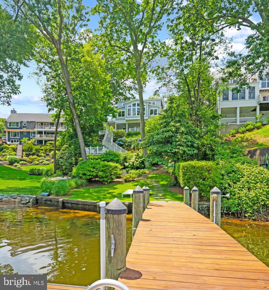 Blending timeless charm with modern luxury, this delightful Cap Cod Waterfront home located in the community of Linstead offers captivating curb appeal, exceptional water views, stylish high-end finishes, and direct access to the Severn River via Yantz Creek. Set on a manicured 0.21-acre lot with 40 ft of pristine water frontage, the property includes a private pier with a 20,000-lb boat lift, jet ski lift, waterside entertaining area, and boathouse with a scenic rooftop deck. Originally built in 1971, the home underwent a stunning transformation in 2016 resulting in over 3,000 sq ft of refined living space. The upper-level features 3 bedrooms and 2 full baths, including a luxurious primary ensuite with a marble double vanity, soaking tub, glass-enclosed shower, walk-in closet, and water closet. A main-level 4th bedroom or office with an adjacent full bath adds flexible living space. The open-concept main level is the heart of the home, showcasing hardwood floors, coffered ceilings in the dining area, vaulted ceilings in the great room, crown molding, and walls of windows that flood the space with natural light and panoramic water views. The chef’s kitchen is outfitted with custom cabinetry, quartz countertops, a French La Cornue range, and a cozy breakfast nook overlooking the water. A charming front den with built-in bookcases and a fireplace adds warmth and character. The finished lower level offers a family/rec room, 2nd fireplace, full bath, laundry area, and direct access to 2-car garage with EV charging. Just outside, a covered patio leads to the boathouse, outdoor entertaining area and pier. The voluntary community association offers amenities like private beaches, a pier, pavilion, firepit, playground, summer beach camps, and regular social events. Located just minutes from downtown Severna Park and a short drive to Annapolis and major commuter routes, this home truly captures the essence of waterfront living in a picturesque close-knit neighborhood.