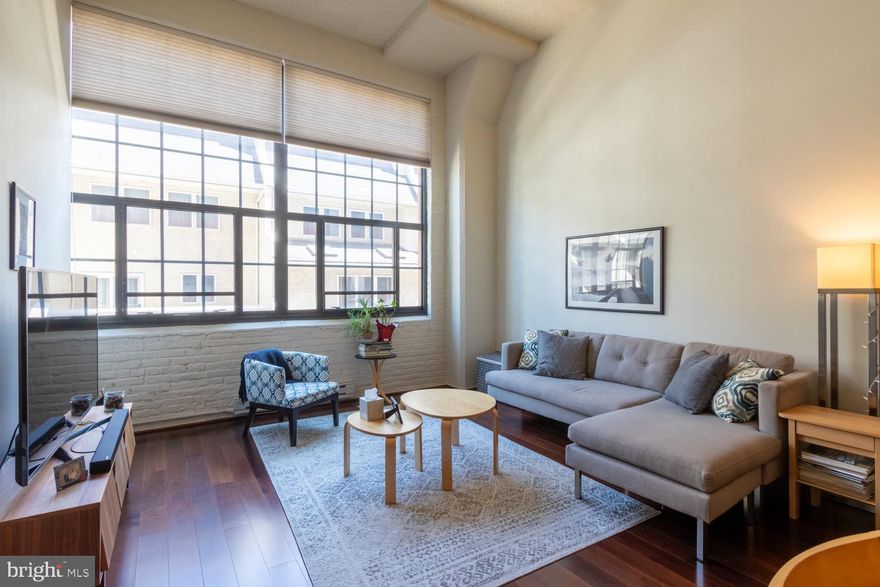 Enjoy waterfront living in the award-winning Locust Point Condominiums  Residence #212 is an EXTRA-WIDE, 761 sq. ft. loft-style residence where industrial blends with modern convenience.  See the difference that a 13'9" wide living area makes! This hip and spacious home features soaring ceilings and a dramatic wall of oversized industrial windows offering tranquil views and abundant natural light. The smartly designed layout includes a raised platform bedroom (9'8" x 11'7") with a large closet. A full bath also houses stackable washer & dryer.  The contemporary kitchen is equipped with plenty of  cabinetry with soft-close drawers, generous countertop work areas, and a large breakfast bar. Wood flooring is throughout the main living areas. Recent upgrades include a new $11K HVAC system (2022) with an Ecobee Smart Thermostat, ensuring year-round comfort and energy efficiency. Residents enjoy a full suite of amenities, including a fitness room,  patio area, on-site dog walk, personal storage locker on the same floor, elevator access, and on-site property management. Garage bike storage when available. The building is pet-friendly (up to 2 pets) and ideally located near the Schuylkill River Trail, University City schools, and this quiet, chic, Fitler Square neighborhood is just a short walk to Rittenhouse.
Urban sophistication and convenience come together in this stylish and serene city retreat.