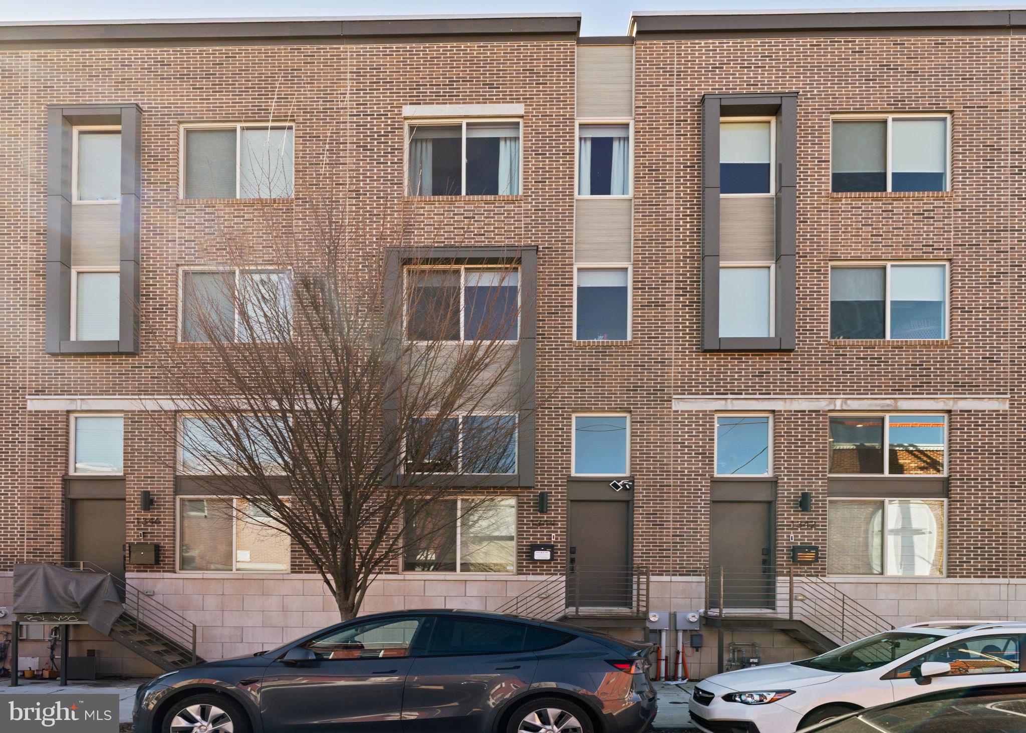 Discover the ultimate blend of sophistication, comfort, and convenience at Smith School Townhomes, this luxury rental in Point Breeze offers 2-car parking in this private gated community. Nestled in the heart of Point Breeze, this home places you minutes from center city, dining, shopping, and entertainment options.
As you enter, be greeted by a grand living room bathed in natural light, featuring soaring 14-foot ceilings that create an airy, open atmosphere. The floating staircase leads you to a lofted dining area and a gourmet kitchen that’s perfect for entertaining. With quartz countertops, marble tile backsplash, custom-built cabinets, and top-of-the-line Bosch stainless steel appliances, this kitchen is as functional as it is beautiful. Off the kicthen is your private deck, the ideal spot for morning coffee. Walk down a set of stairs to access the oversized garage with a EV charging station, a convienet powder room, and finished basement that can be your home gym or enetertainment room. Head upstairs to the 2nd floor, to find two generously sized bedrooms, each with ample closet space, and a stylish hallway bathroom featuring a deep soaking tub. A laundry closet with LG washer/dryer completes this level. The entire top floor is dedicated to the primary suite, offering a true sanctuary, with a large walk-in closet. Double barn doors open to reveal a breathtaking bedroom, a massive walk-in closet, and a spa-like bathroom designed for indulgence. Enjoy heated floors, a floating dual vanity, a glass-enclosed shower, and a 70" soaking tub that invites you to unwind. The hallway wet bar with mini fridge and powder bathroom ensure your private space remains just that – private. Just steps away, your private roof deck awaits, offering 360-degree city views and a green roof that’s perfect for gatherings or quiet moments under the sky with views of the city skyline. This residence offers unparalleled privacy and peace of mind, complete with an automatic security gate to your 2 car parking, exterior Ring security cameras & doorbell. Enjoy the ease of a MyQ smart home garage door opener, an EV charging station for eco-conscious living, and the added convenience of snow removal services during winter months. Available June 1st.