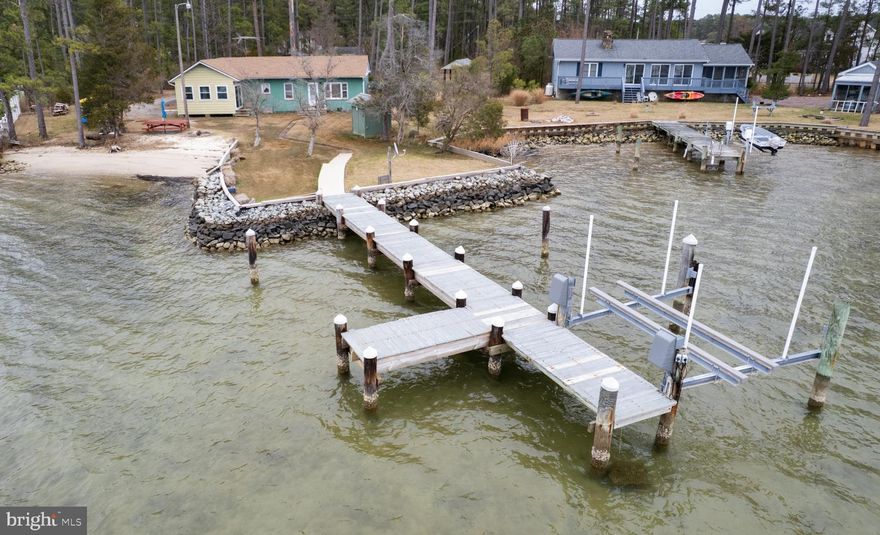 Waterfront living doesn’t have to break the bank! Tucked along the peaceful banks of Brooks Creek, this hidden gem at 810 Seabreeze Road offers the quintessential Eastern Shore retreat. The property includes two parcels totaling approximately 1.33 acres, providing plenty of space to relax, expand your outdoor living, and fully embrace the coastal lifestyle. The cozy, fully furnished cottage features 2 bedrooms and 1 full bath and has been lovingly maintained, making it truly turn-key for weekend getaways, hosting family and friends, or operating as a short-term rental. A generous sunroom serves as the perfect hangout or game room, a comfortable space to pick crabs, or even overflow sleeping accommodations for guests.
Enjoy peace of mind knowing the home has received several major updates, including a new roof in 2022, septic system in 2023, heat pump in 2024, and well in 2025, windows in the sunroom 2023. Outside is where this property truly shines, featuring a private sandy beach ideal for launching kayaks or paddleboards, relaxing with a beach chair, or gathering around a sunset campfire. A private pier with a 10,000-lb boat lift conveys with the sale, giving you quick water access to the Chesapeake Bay for fishing, crabbing, and boating adventures, with easy day trips to Calvert Cliffs, Solomons Island, Taylors Island, and Susquehanna Beach. Several outbuildings provide convenient storage for water toys and equipment. The additional parcel included in the sale is not suitable for residential construction, but offers excellent flexibility for a shop or pole building, RV or camper pad, or simply additional outdoor space. Don’t miss this rare opportunity to own affordable waterfront property in Dorchester County—your Eastern Shore escape awaits.