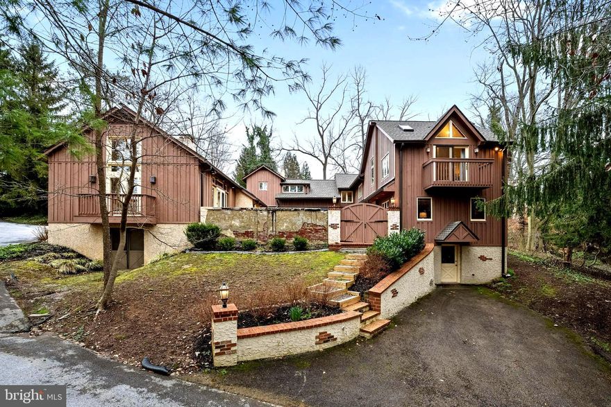 Welcome to a piece of history at this timeless carriage home. Originally constructed in 1917, this unique residence exudes character with fascinating origins as a carriage house with attached stables, artfully converted into a dwelling that seamlessly marries historic charm with modern comfort. This residence has seen additions over the years, carefully integrating modern amenities while preserving the original character that makes it truly special. The property is a testament to architectural ingenuity and timeless design, creating a warm and inviting atmosphere, boasting 5 bedrooms and 4.5 baths, nestled in the sought-after Wayne community within the award-winning Radnor School District.
Step inside to discover a thoughtfully designed interior with a state-of-the-art Kitchen, providing the perfect blend of style and functionality (2022), comprising elegant Wellsford cerused rift sawn white oak cabinets, honed quartzite counters, top of the line Wolf double ovens (steam) and induction cooktop, Bosch Benchmark Line Refrigerator/freezer and Dishwasher, and Sharp microwave/air fryer drawer. A spacious breakfast area overlooks the perennial side garden making the entire space a great entertainment area overlooking the enclosed inner courtyard, which becomes an extension of the living space, seamlessly blending indoors with outdoors. An ideal space for entertaining, reflecting, watching over young kids or pets! Whether you seek a quiet moment of serenity, a secure space for toddlers/pets, quiet reading or a grand social gathering, this original space with lush plantings and brick pavers will captivate and enhance your overall living experience.
The Great room was a later addition with cathedral and beamed ceilings, skylights and patio doors with balconies. One set leads out to the enclosed courtyard. It features  a giant wood fireplace and hardwood floors. On the opposite side of the kitchen are the converted stables now serving as a den with beamed ceilings and exposed brick. An original barn door leads from there to the dining room with beamed ceilings and pellet stove fireplace. For convenience, there is a first-floor bedroom, with double closets and full bathroom. This could serve as an office or an in-law suite, with a door to the courtyard offering modern convenience and historic ambiance.
Upstairs on two levels are 4 additional bedrooms, all with hardwood floors and  wood blinds. The elegant primary bedroom has a cathedral ceiling, skylights, french doors (with balcony) and a walk-in closet. The bathroom was totally replaced (2023) with porcelain tile, dual sinks and oversized frameless shower. 2 more large bedrooms at this level, with double closets, have access to the hall bath with a shower over soaking tub. The remaining bedroom sits above the kitchen, oversized witha bathroom suite including a large soaking tub, separate tiled shower, dual sinks, towel warmer and walk-in closet.
There are 2 finished lower-level areas both with external access. One offers the laundry utility space along with finished open area and a crawl space for storage. The other houses some mechanicals and more storage.
The house sits back from the road on a .97ac lot. Outside are several open spaces with mature plantings in a picturesque setting, including two fenced areas, ideal for pets or kids’ play area.
The entire roof and 11 skylights were replaced in 2019. A detached 2-car garage complements the property, with Wifi enabled door openers (2021) providing convenience and additional storage. Ample space for parking additional cars too.
Explore the possibilities this hidden retreat presents, where history meets contemporary living. Chanticleer Park, The Willows and the Radnor Trail just minutes away. A perfect balance of tranquility and accessibility to nearby amenities and conveniences in downtown Wayne. Convenient for all commuter routes by rail or road, to center city Philadelphia, New York and Philadelphia international airport.