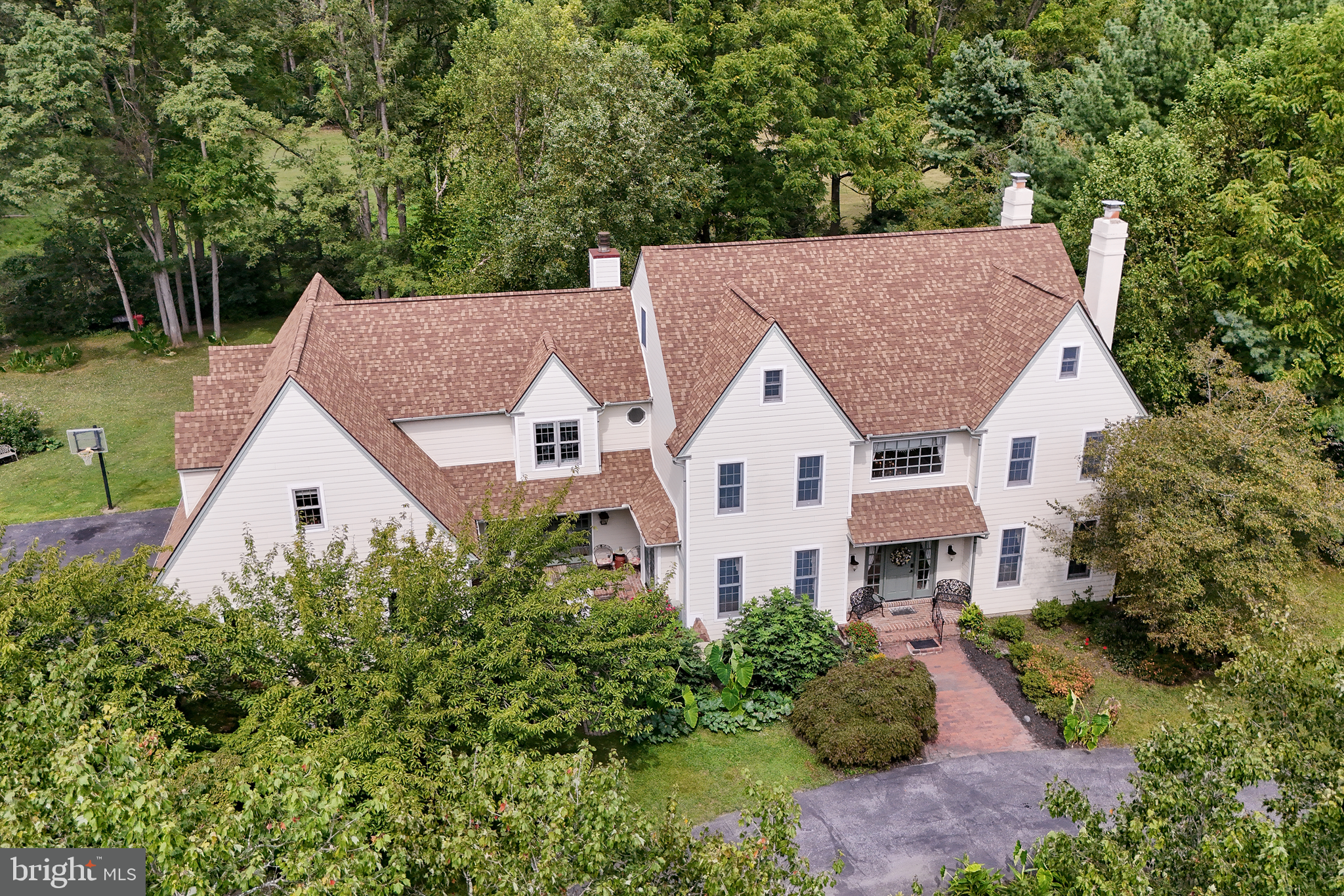 Set along the tree-lined streets of Baneswood, a secluded community designed for privacy, this impressive residence with updated Hardie siding offers a spacious, versatile floor plan set on 1.3 acres highlighted by seasonal flowers, mature plantings, and a circular driveway. This home boasts over 4700+ sqft of living space plus another 1275 sqft of bonus space in the partially finished basement. Interior highlights include sweeping ceiling heights, front & rear staircase, three fireplaces, a fantastic amount of closet & storage space throughout with a Thoughtful design that allows for flexible living, easily accommodating multi-generational needs. The main floor showcases a dramatic center hall foyer flanked by the formal living and dining rooms. A generously sized kitchen featuring a commercial grade Sub-Zero refrigerator, abundant cabinetry, pantry, and an oversized island with seating with a desirable layout open to the morning & family rooms. A home office with access to a private courtyard could double as a first-floor bedroom with a full bath nearby. Additional conveniences include main-floor laundry with a full bath, a guest powder room, and interior access to the rear paver patio and the oversized three car garage. Upstairs, the expansive primary suite includes a private bath and walk-in closet, an additional bonus suite, plus three additional generously-sized bedrooms sharing a full hall bath. A walk-up attic provides a tremendous amount of convenient storage or the potential for future living space. The partially finished basement with half bath offers a spot for additional living areas plus even more storage space. System updates since 2018 include: 2 furnaces, 1 central air, septic tank & well maintenance. Perfectly located near plenty of shopping & dining options, Longwood Gardens, parks, and festivals, with easy access to Wilmington and Philadelphia. This home is an exceptional value in today's market and a rare opportunity to enjoy life in one of Kennett Square's most sought-after neighborhoods.