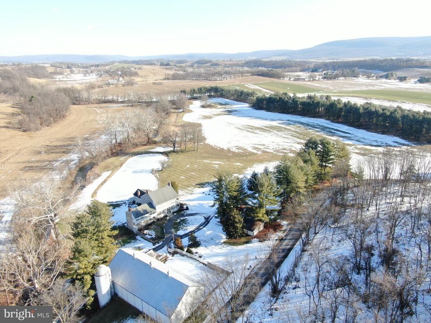 Welcome to one of the most distinguished properties in Washington County, Maryland—a truly rare find that seamlessly blends history, elegance, and modern comforts. Nestled on 23± acres of pristine land, this extraordinary estate is an idyllic retreat, offering a private sanctuary surrounded by nature. The property boasts over 400 feet of frontage along the Little Antietam Creek, a serene half-acre pond, lush woodlands, and 10 acres of tillable farmland, creating a harmonious balance of natural beauty and potential.

At the heart of the property stands a magnificent limestone farmhouse, thoughtfully restored to preserve its historical charm while incorporating contemporary amenities. The home’s grandeur is evident from the moment you step inside, with soaring 10-foot ceilings on the main floor and 9-foot ceilings on the second. Rich hardwood floors flow throughout, adding warmth and character to every room, while multiple working fireplaces enhance the home’s timeless appeal.

With 5 spacious bedrooms—including a luxurious primary suite with an en suite bath, a generously sized walk-in closet, and stunning views of the surrounding landscape—this home provides ample space for both relaxation and entertaining. The 4.5 bathrooms are tastefully designed with premium finishes, and the well-appointed kitchen offers picturesque views of the pond and creek, making it a perfect space for culinary creativity.

Entertaining is effortless in the elegant dining room, while the inviting family room and den with a cozy pellet stove offer intimate spaces for unwinding. The expansive living room, with its soaring cathedral ceiling, exposed beams, and stone fireplace, serves as the heart of the home—its French doors opening to the outdoor patio, hot tub, and spectacular views of the property.

Designed with both function and form in mind, the home also includes an office with towering built-in bookshelves, and a variety of storage spaces.

The property’s outbuildings enhance its appeal, with a 3-car detached garage featuring a loft, a 42x90 bank barn, and a 6x15 milk house—perfect for a variety of uses, from hobbies to farming pursuits.

This exceptional estate represents a once-in-a-lifetime opportunity to own a meticulously cared-for home, rich with history and unparalleled in its beauty. Do not miss your chance to experience the serenity and luxury of this remarkable property. 

This property will be offered as a multi-parcel auction meaning multiple tracts will be available for sale. Buyers may come and purchase the individual tracts, or as a whole property. 

Tract 1: Incredible home and outbuildings on 23.47± acres
Tract 2: 4.5± acres of vacant wooded land located across the road

This property will be offered at auction on Tuesday March 11, 2025 @ 3:00pm. The List price in no way represents a minimum, starting, or acceptable bid.