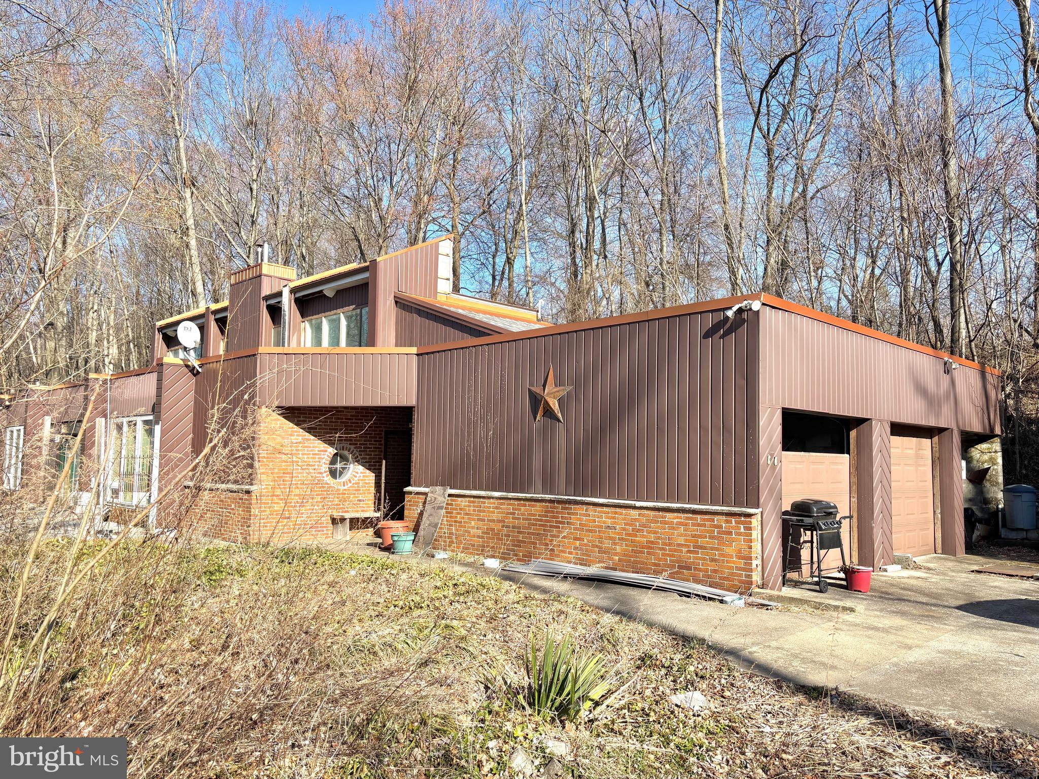 Nestled on 2.62 wooded acres in Derry Township, this unique home offers both privacy and convenience, just minutes from local amenities. Large windows capture scenic mountain views while filling the space with natural light. Designed for easy one-floor living, the layout includes a spacious primary bedroom, a comfortable living room, a formal dining area, and a fully equipped kitchen with ceramic tile flooring. Historic doors throughout the home add charm and character. A standout feature is the greenhouse room with a soaring 20-foot ceiling, perfect for gardening. The attached two car garages provide ample storage, while the detached garage includes a workshop and upper-level office and bonus rooms, ideal for work, hobbies, or creative ventures. This three-bedroom, two-bath home offers multiple heating options, including a newer mini split system, baseboard hot water heating, and a cozy pellet stove. With some TLC, this property is ready for your personal touch. Do not miss this opportunity to make it your own in Lewistown!