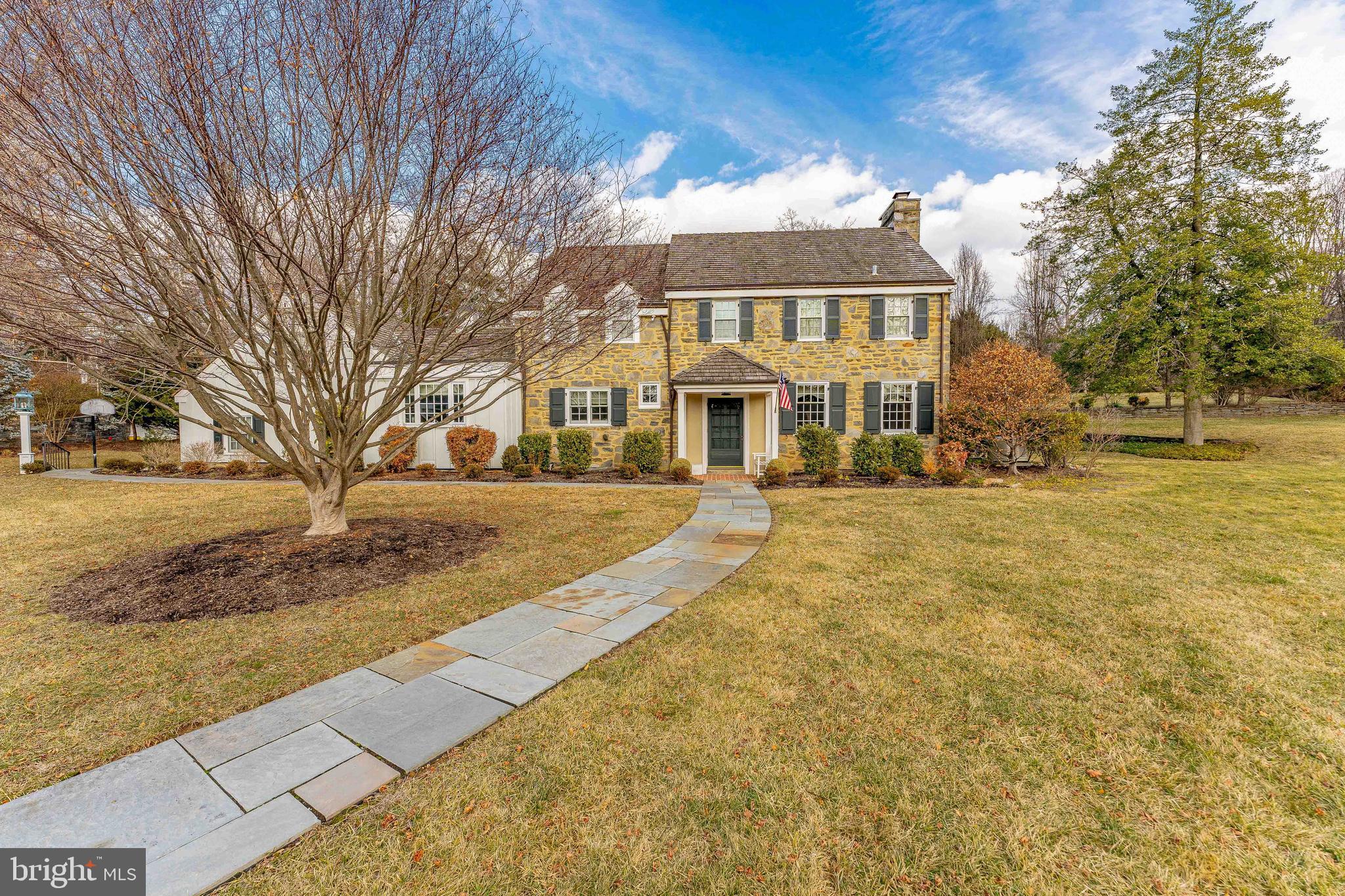 Welcome to 620 Montgomery School Lane – An Exquisite Residence in Lower Merion Township. Step into luxury with this stunning 5-bedroom, 4-full bath, 2-half bath single-family home in desirable Wynnewood. Featuring a beautifully crafted stone exterior, this residence offers a 2-car garage and ample driveway parking. There is also an attached shed behind the garage, providing ample storage space. As you enter, you are greeted by an elegant foyer with gleaming hardwood floors and custom crown molding that extends throughout the home. The spacious hallway one step up, leads to a walk-in coat closet and elegant sconce lighting. The entire home is beautifully appointed with custom woodwork, showcasing unparalleled craftsmanship and an exquisite attention to the finest details. To the right, the inviting living room boasts hardwood floors and a cozy gas fireplace, framed by two windows that bathe the room in natural light. Beautiful Pella windows are found throughout the home. Straight ahead, the expansive family room features a wood-burning fireplace, custom built-in bookcases, and a door leading to the back patio. To the left of the foyer, a powder room offers easy access for guests. The formal dining room combines hardwood and brick flooring, with built-in china cabinets and a sliding glass door to the massive rear brick patio for seamless indoor-outdoor entertaining. The butler's pantry with another china cabinet opens into the gourmet kitchen. The chef’s kitchen is a true centerpiece, featuring a large island with a gas cooktop, granite countertops, and a breakfast room with vaulted ceilings and exposed beams. The space is filled with natural light and offers access to the laundry room and a staircase leading to the private bedroom above, currently being used as a home office. The bedroom/office, with plush carpet and four large windows, offers a quiet retreat, while a pocket door leads to a full bathroom with tile floors, granite countertops, and a steam shower with a built-in bench. Upstairs, the primary suite is a luxurious retreat with hardwood floors, two walk-in closets, and a spa-like en-suite bath. The bath features a granite sink vanity, a tile shower with glass doors, and refined finishes throughout. Down the hallway, a third full bathroom with a tub/shower combination serves the additional bedrooms. The second and third bedrooms are both spacious with multiple windows and ample closet space. The fourth bedroom has access to a Jack-and-Jill bathroom, also connecting to the primary suite. Additional features on this level include a linen closet and access to a walk-up attic with a large walk-in cedar closet, ideal for storage. The lower level includes a partially finished basement, offering a warm, wood-paneled family room with an expansive walk-in closet for your additional storage needs. An additional closet is currently used as a wine cellar, with built-in shelving. The basement also houses essential utilities, storage areas and an additional powder room. A standout feature of this home is it is located on a desirable corner lot and has a partial house generator. This home is perfectly positioned within the award-winning Lower Merion School District and provides easy access to local dining, shopping, and recreation. 620 Montgomery School Lane is not just a house—it’s a lifestyle. Don’t miss the opportunity to make this exceptional home yours!