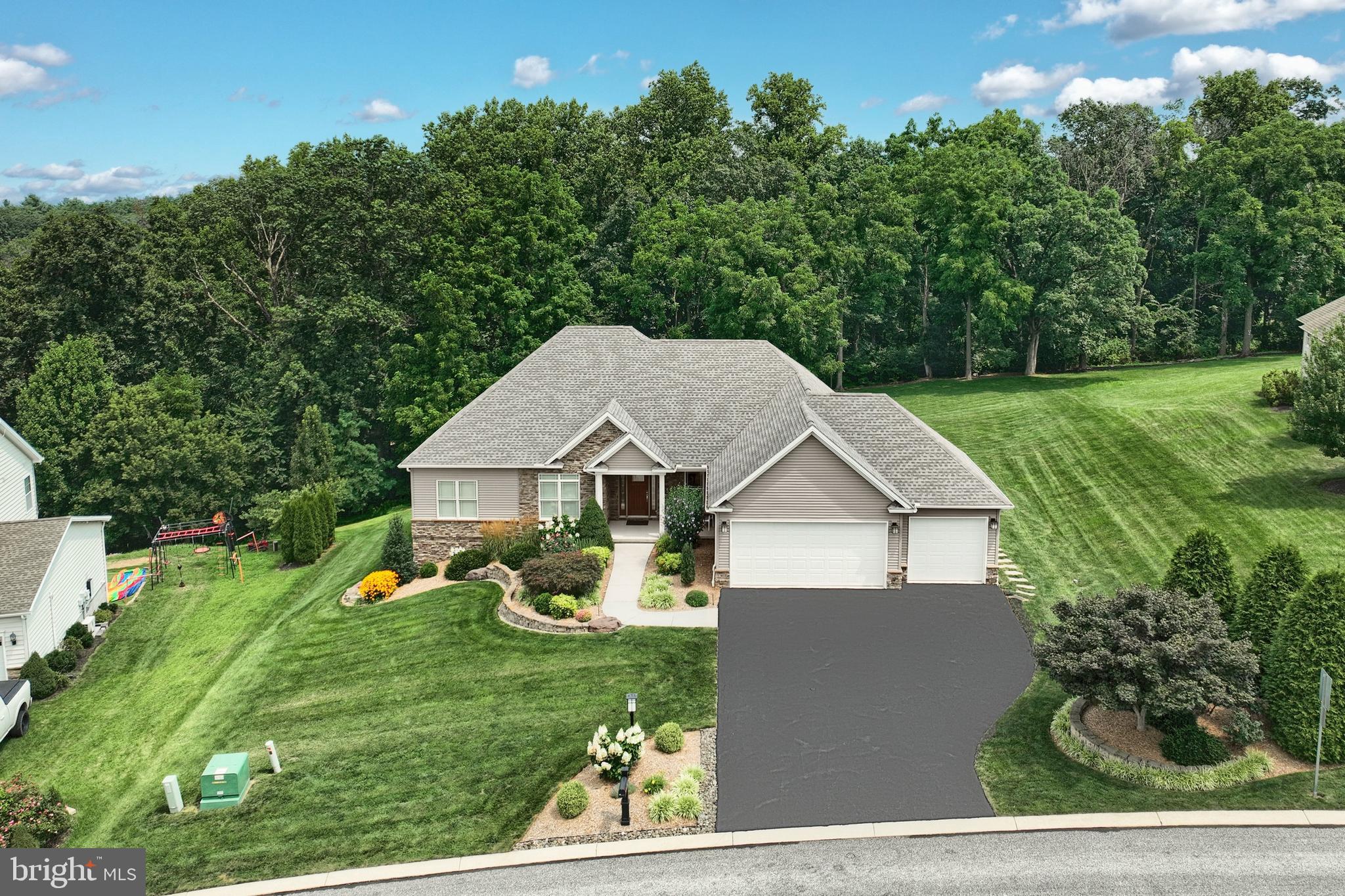 This exceptional 5-bedroom, 3.5-bath, 3 car garage, home in Conewago Valley School District showcases the meticulous care and stewardship of its sellers. Every detail reflects thoughtful maintenance and quality, from the warm acacia wood floors to the carefully selected finishes and decor throughout. Abundant natural light streams through Pella windows and doors highlighting the spacious welcoming atmosphere! Step inside to an open and inviting main level. To the right, a stairway leads to the finished lower level, while straight ahead, the living area features a soaring cathedral ceiling, stone gas fireplace and a Palladian window. The space flows seamlessly into the dining area and kitchen, which boasts granite countertops, a large island, stainless steel appliances, and convenient access to the laundry room, powder room, and oversized 3-car garage. Exiting to the deck and beautifully hardscaped patio, the home offers indoor-outdoor living at its finest. The main level includes 3 bedrooms, 2.5 baths total, highlighted by the primary suite with a three-tier tray ceiling and walk-in closet. The en suite bathroom features a customized tile shower with built-in bench. The lower level expands your living space with a finished family room, walk-out to the patio, 2 additional bedrooms with large windows overlooking the backyard (one currently used as an office), 1 full bath, a workout room, and ample storage. Recent updates ensure convenience and peace of mind, including a new refrigerator (2025), new microwave (2025), new well pump (2023), and new hot water heater (2024). Set on over half an acre with a backdrop of trees, this home offers a private, picturesque setting for relaxing or entertaining. The seller is also providing a ONE YEAR home warranty (see documents.) With meticulous care and thoughtful updates throughout, this home truly presents an exceptional opportunity to enjoy a lifestyle of comfort and convenience.