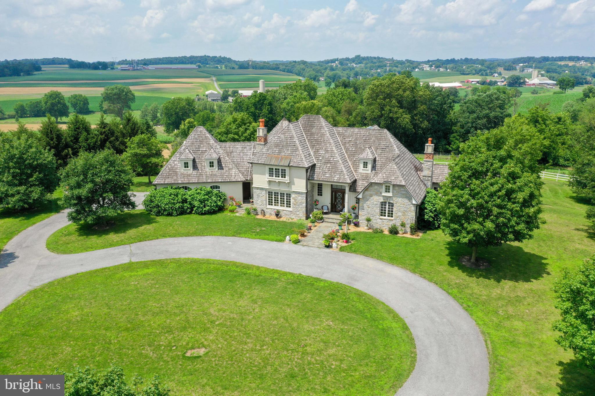 This exceptional and inspiring Rapho Township manor sits on over 40 acres of bucolic paradise. A long lane aligned with cornfields on both sides leads to this magnificent manor of over 7300 square feet, boasting 4 bedrooms, 4.5 baths, and one-of-a-kind features, designs and amenities. The sprawling foyer makes a grand entrance with detailed molding and mahogany stairs, exposed wood, exotic tile and so much more. It flows seamlessly to the stunning and majestic atrium. As you enter the atrium you will cross through a set of French doors and be wowed by the grand window display, cathedral ceiling with skylights, slate roof overhanging, custom artwork, hand blown glass, and architecture by John Hughes. An immaculate 1st floor owner’s suite is a delight with bamboo flooring, detailed trim, cove lighting, 2 walk-in closets, and corner gas fireplace. The private bath is mesmerizing with dual vanities, soaking tub, walk-in shower, speakers, and more. A large bonus room off the owner’s suite dazzles with counterspace, cabinets, murals, and solid granite sink that could be used in a number of ways. A glamourous gourmet kitchen is ideal for cooking, baking, and entertaining with oversized center island, breakfast bar, granite counters, multiple sinks, top notch appliances, tile backsplash, sub-zero wine fridge, and so much more. It looks into the family room complete with vaulted ceiling, wood fireplace, atrium access, and grand window display with scenic country views. Plus, a balcony from the 2nd floor looks down on this amazing space. For more formal occasions is the private dining room with fireplace, coffered ceiling, and crisp views of the front cornfields. A first floor laundry room features custom hand painted tile, counters, copper sink, cabinets, 2 washers, and 2 dryers. There is a walk-in pantry closet with built-in storage and stainless-steel countertops. A hall outside the pantry and laundry room has a soapstone sink, custom hand painted tile, and cabinet and counter space. Plus, many storage closets lead to the attached 2-car garage and staircase to an upper section of the house containing a spacious bedroom, full bath and walk-in closet. As you make your way up the main front stairs to the upper level, notice the quality design and custom craftsmanship with mahogany wood. At the top of the stairs there are built in bookcases with ladder and bench seats overlooking the atrium and the exterior views. A great place to relax, read a book, and drink a cup of tea. There are 2 spacious bedrooms with walk-in closets that each have wonderful views and share a lovely Jack & Jill bath. The one bedroom has the stain-glass doors that open to the balcony overlooking the family room. A finished daylight walkout lower level has endless possibilities with a full bath, space for a rec room, game room, entertainment center, in home gym, hobby room, etc. There is also a convenient staircase that connects to the garage. Other outstanding features include a security system with 8 cameras, driveway sensor, 2 barns and 3 pastures, expansive deck accessible throughout many rooms of the home, an entire house water filter system, Superior wall foundation, generator, radiant floor heat, central vac, and so much more. Schedule a showing today to see this majestic manor.