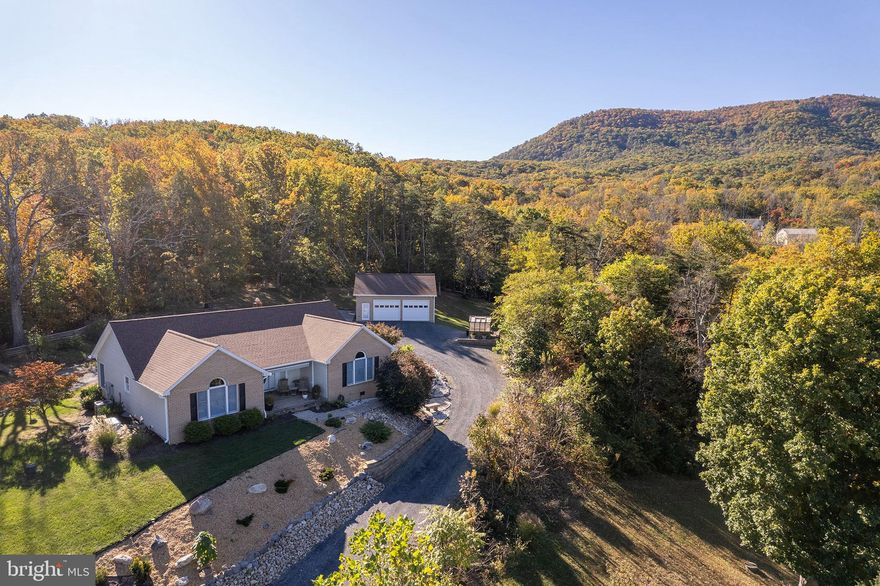 Nestled in the serene Stoney Mountain Estates, this charming ranch-style home offers a perfect blend of comfort and functionality. With 1,928 sq. ft. of thoughtfully designed living space, this residence features two spacious bedrooms and two full bathrooms, including a luxurious primary bath with a walk-in shower and tub. The heart of the home is the inviting country kitchen, complete with upgraded countertops, stainless steel appliances, and ample table space for casual dining. Step outside to discover a beautifully landscaped 2-acre lot that backs to trees, providing a peaceful retreat. Enjoy the scenic vistas from your patio or porch, perfect for morning coffee or evening relaxation. The extensive hardscape and stone retaining walls enhance the outdoor charm, while the detached garage and additional shed offer ample storage. Located in a tranquil mountain setting, this home is just a short drive from I-81 & I-66, ensuring easy access to nearby amenities. The property is equipped with modern security features, a water treatment system, and a whole-home generator for added peace of mind. With its combination of privacy, natural beauty, and convenient location, this home is a true sanctuary waiting to welcome you.  NEW Roof and Furnace in 2025!  Hiking trails, Skyline Drive, Shenandoah River, and charming small towns are all nearby, too!