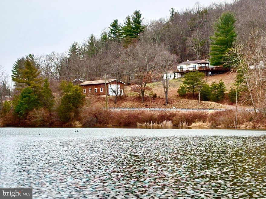 Location! Location! Location! This well maintained three bedroom, two bath home overlooks the Parker Hollow Lake and offers splendid views  and panoramic sunsets. Owner  will entertain selling completely furnished. A turnkey getaway to usher in spring in style! Unrestricted, the property offers not only an attached garage, but also a 
20'x54'x12' stick built garage, with a concrete floor,  electric garage door opener and water available.. The house is laid out well, meticulously maintained and the third bedroom on the lower level is currently used as a study. On cold winter nights, the Fisher wood stove is great to cozy up to in the family room..  The kitchen offers a breakfast bar, a filtered water faucet, dishwasher, flat top range and refrigerator,  just off the dining area. The back yard and wrap around deck backs to trees,  has a shed, a chicken coop, grilling area and fire pit.
The property  adjoins Natural Resources Conservation Service property that encompasses the Parker Hollow Dam, and  is managed as a recreational spot in a relatively remote, quiet setting. The 34.5-acre impoundment was built to provide flood control and water supply for Hardy County and creates Parker Hollow Lake, which is fed by Camp Run and Parker Hollow.. It has a  maximum depth of 35 to 40 feet and features a  parking area,, a concrete boat ramp and dock, making it a secluded spot for fishing and boating and is known  for stocked species including  Trout, Bluegill, Largemouth Bass, and Channel Catfish. . Only electric motors,  kayaks, canoes, paddle board and the like are permitted. Conveniently located only a couple of miles off the Rt. 48 Baker Exit, it's 15 minute drive Moorefield, forty minutes to Winchester and just over an hour to Davis,  to  enjoy skiing, hiking  and more mountain biking trails!   A perfect weekend home or full time residence or VRBO/Airbnb!