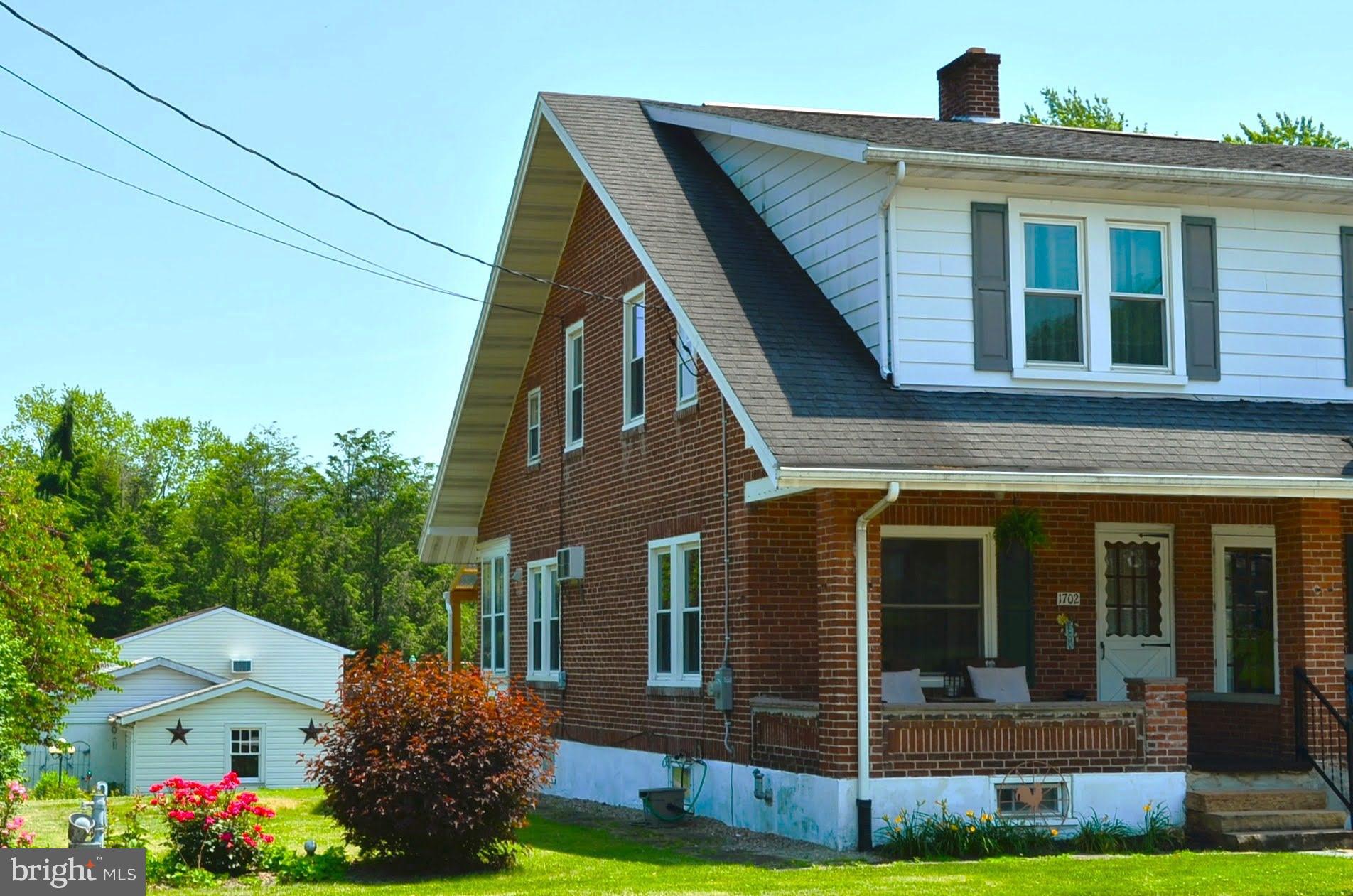 This charming home is nestled on a beautifully landscaped corner lot in a neighborhood with quiet small-town atmosphere. It is clean, well maintained and move-in ready so you can relax and start enjoying your new home immediately. The main level is cooled by a built-in wall unit and ceiling fans, has natural wood flooring. It consists of a living room, dining room, half bath and kitchen which was fully remodeled in 2024. The remodel includes new cabinets, countertops, sink, vinyl flooring, dishwasher, range and refrigerator. The mudroom, off of the kitchen, has a new back door and storm door that lead to a small covered back deck, built in 2024, with composite decking. The natural wood flooring that continues upstairs through the bedrooms and closets. The full bath has a ceramic tile shower surround and half walls and updated vinyl flooring and two shelved closets. The attic storage area is accessed in the hallway by a set of pull-down folding stairs. The full basement provides plenty more storage space and laundry hook-up. Outside enjoy multiple perennial flower beds, and the serene church bells, plenty of shade on the front porch and from trees and a bit more privacy on the rear deck. The yard is ready for outdoor activities and grilling on the cement patio. The local park is just a short walk away. An oversized, one car detached garage with a new automatic door and an enclosed carport with double doors and additional paved off-street parking provide plenty of space for multiple vehicles and recreational toys. Additional recent mechanical updates include: Insulated vinyl replacement windows in 2009, well treatment system in 2020, new furnace in 2022 and new upgraded electrical panels in the house and garage in 2024. The home is a rare find with a blend of rustic charm, functionality, abundant storage, outdoor space, and off-street parking combined with a location that offers a tranquil setting while remaining a short drive to shopping, restaurants and other locations. Call today for a tour.