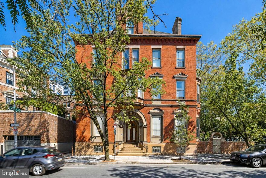 Welcome to your own piece of Philadelphia history at Chandler Place — an extraordinary residence in the heart of coveted Fitler Square,  with the convenience of private deeded 1-car parking.

Approached through a tranquil courtyard beneath a canopy of mature trees, the building welcomes you through a private entrance, setting the tone for the refined blend of heritage and elegance that unfolds inside.  Upon entering through the double glass-enclosed foyer, a beautifully detailed decorative plaster ceiling immediately highlights the home’s historic craftsmanship.
The formal living space impresses with soaring ceilings, oversized windows, and original architectural details. Hardwood floors with intricate walnut and mahogany inlays, elaborate moldings, and beautifully preserved woodwork reflect craftsmanship rarely found today. Ideal for entertaining, the visually stunning formal living area greets you with meticulously preserved parquet floors, intricate molding and woodwork, anchored by a grand fireplace that adds warmth and architectural presence. The kitchen features granite countertops, white shaker-style cabinetry with abundant storage, and stainless steel appliances including double convection ovens
The main-floor bedroom suite features dramatic 14-foot ceilings, expansive windows, original parquet flooring, a mahogany mantel fireplace, and a generously sized closet. Thoughtfully designed with a coffee bar and its own en-suite bath, the space offers both comfort and flexibility.
A sweeping staircase leads to the second bedroom suite, accompanied by a versatile office area near the landing. Enclosed laundry area with brand new washer & dryer . This private retreat features a decorative fireplace, large custom wardrobe, and a beautifully appointed spa-inspired bath with a Hansgrohe steam shower, sculptural soaking tub, double vanity, and floor-to-ceiling stone tile, creating a serene atmosphere of modern luxury .
Originally designed in 1904 by renowned architect Theophilus Chandler for the Episcopalian Bishop of the Pennsylvania Archdiocese, this distinguished mansion represents a remarkable chapter of the city’s architectural legacy. In 1980, celebrated architect Otto Spur thoughtfully transformed the estate into exclusive condominium residences, preserving its historic grandeur while introducing modern comfort. Today, this residence offers the opportunity to become the next steward of a significant Philadelphia landmark.
This pet-friendly residence enjoys one of Philadelphia’s most desirable locations — perfectly positioned minutesfrom Rittenhouse Square and the Schuylkill River Trail, with world-class restaurants, boutique shopping, and cultural landmarks just moments away.

Chandler Place offers a rare opportunity to live within one of Philadelphia’s enduring architectural treasures, where history, craftsmanship, and modern city living converge.