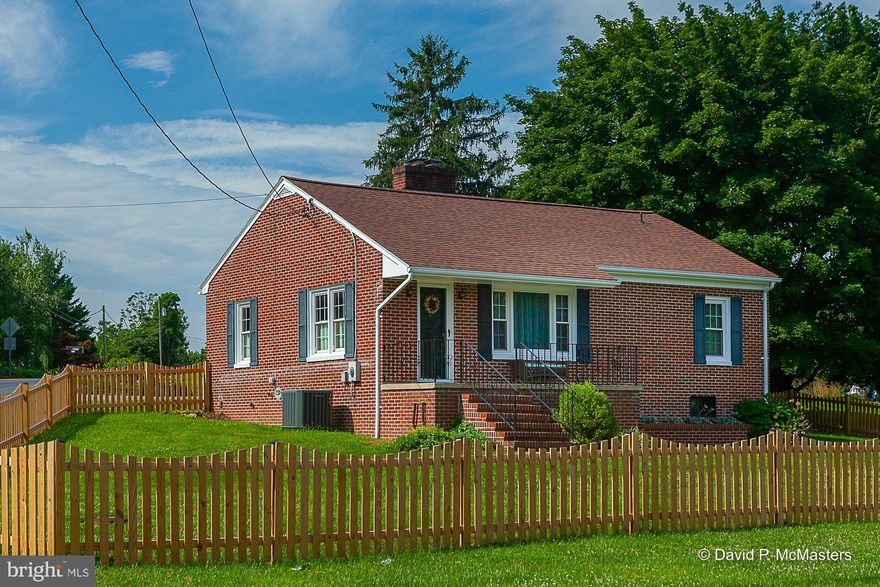 Cute as a button and move-in ready, this cozy Ranch/Bungalow style home is conveniently located moments from the heart of Inwood and Interstate 81!  Solid built, all-brick exterior with car port and step-up front porch set on .44 acres.  New wood picket fence installed December 2021 surrounds the front and side yards.
The interior is nothing but cozy!  The living room offers gas fireplace and bay window, dining room with interior shutters, fully equipped kitchen with plenty of white cabinetry, 2 bedrooms, and 1 bath.  Arched doorways and hardwood floors throughout.  Seasonal rear enclosed porch leads to the covered carport.   Heat pump.  Full basement.  Public water and sewer.   Water softener conveys.  NO HOA!