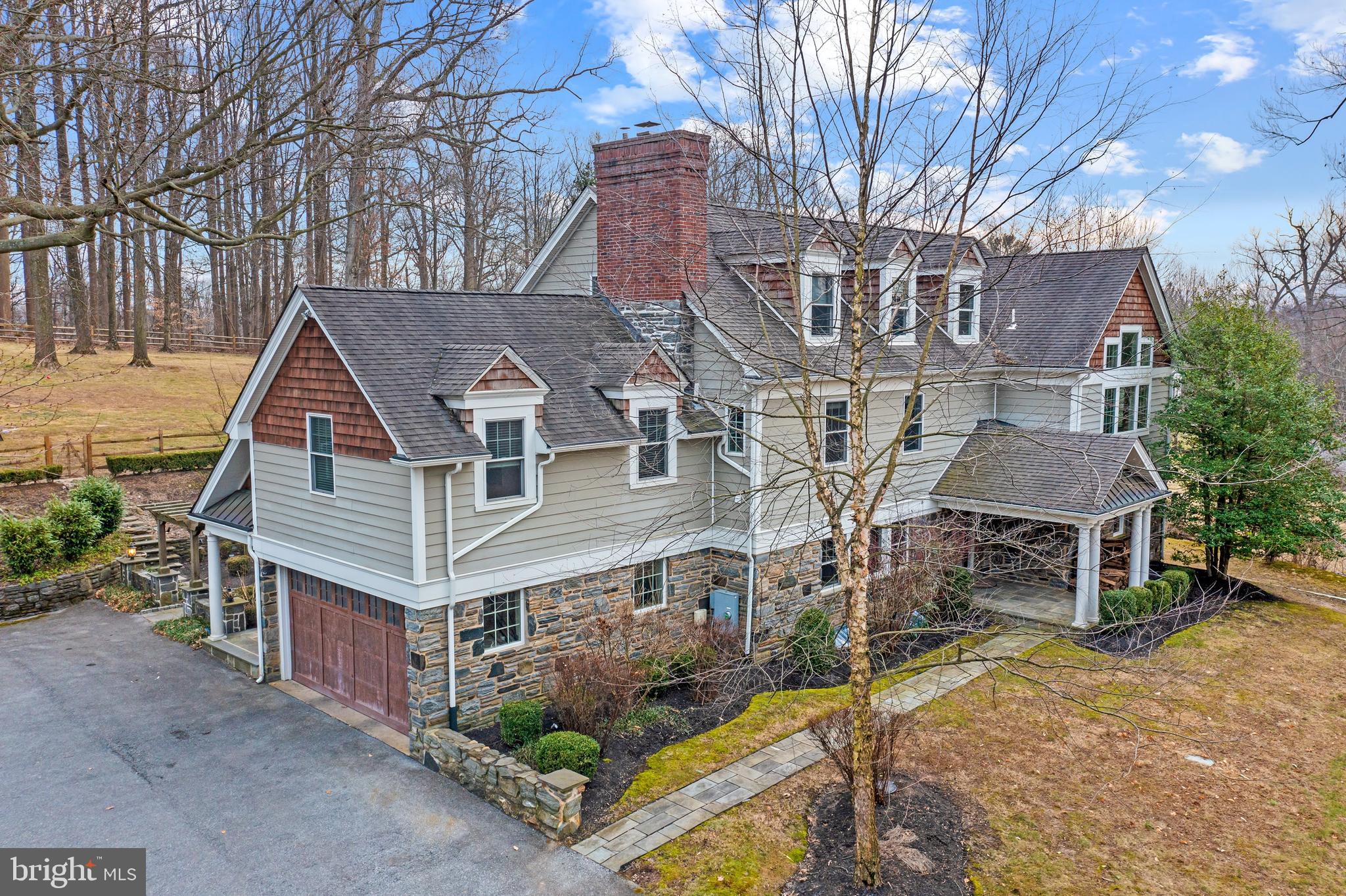 Surrounded by lush greenery on an expansive 1.63 acre lot, this recently renovated manor captivates all with its incredible views, remote privacy, and impeccable details. Located in the highly sought-after town of Haverford, this 6+ bedroom, 5.5 bathroom residence truly exceeds all expectations.
As you approach the long driveway, you are greeted by an extravagant front yard with manicured hedges and vibrant foliage. A flagstone walkway welcomes you to a tasteful wooden front door at the main entrance. Upon entry there is a vast two-story foyer that showcases the extensive open layout and exquisite millwork throughout the main floor, transitional architecture, and decorous finishes that combine established design and modern amenities.
Directly off the foyer to the left sits a bright and airy living room adorned with a brand new wood-burning stone surround fireplace and a classic wooden mantle, handsome chair railing and crown molding, artistic hardwood flooring, and recessed lighting. Make your way across the hall to the formal dining room decorated with an abundance of natural light, a beamed ceiling, direct access to the rear yard stone patio, chair railing, crown molding, and plenty of space to comfortably host endless dinner parties. The dining room seamlessly flows into the gourmet chef’s kitchen equipped with glistening granite countertops and island, stainless steel appliances including a farmhouse sink and 6 burner gas stove and a plethora of wooden cabinetry. A cozy breakfast area with direct access to the rear patio completes the kitchen. Nestled in the rear of the home and open to the kitchen, is the expansive great room anchored by a substantial stone surround gas fireplace, and detailed with oversized windows, ultra high cathedral ceilings with exposed wooden beams, and oversized windows. The main floor is finished with a private office space, a full tiled bathroom with a glass stall shower and a stone floored mudroom that leads to the attached two-car garage.
Take the grand front wooden staircase to the second floor and find your way to the primary suite, which elegantly features a sumptuous sitting area, expansive windows, a large walk-in closet, tray ceiling, hardwood and carpeted flooring, and recessed lighting. The exclusive, zen-like ensuite bath features a dual vanity, intimate soaking tub, and a large glass-enclosed walk-in shower. Three additional bedrooms can be found on this floor, each accented with hardwood flooring and ample closet space. Two bedrooms enjoy a full hall bathroom, with the third bedroom equipped with its own private ensuite bath. Rounding out the second floor is a convenient laundry area. On your way to the third floor, you will come across a quaint reading nook on the landing with a built-in bookshelf. The third and final floor boasts two generously sized rooms that can be utilized as additional bedrooms, office spaces, or play areas complete with a shared bathroom.
The massive lower level of this home has everything you are looking for to host your next gathering of family and friends. This neatly tiled space includes a granite top bar, second living area, large fitness studio area, an immense amount of storage opportunities, and a convenient half bathroom. Exit the home through one of the many main-level glass exterior doors to the recently expanded fenced rear yard. This amazing outdoor living/entertaining area fits seamlessly into the property with a brand-new custom stone patio, yards of rolling green grass and mature landscaping. Ask for the architectural plans for a swimming pool in the raised area.
Situated in the heart of Delaware County, this home sits within a few mile radius of countless golf courses with close proximity to Merion Golf Club, restaurants, and major shopping. 217 Marple Road finds itself in the Haverford School District, with many prestigious private schools in the area as well.