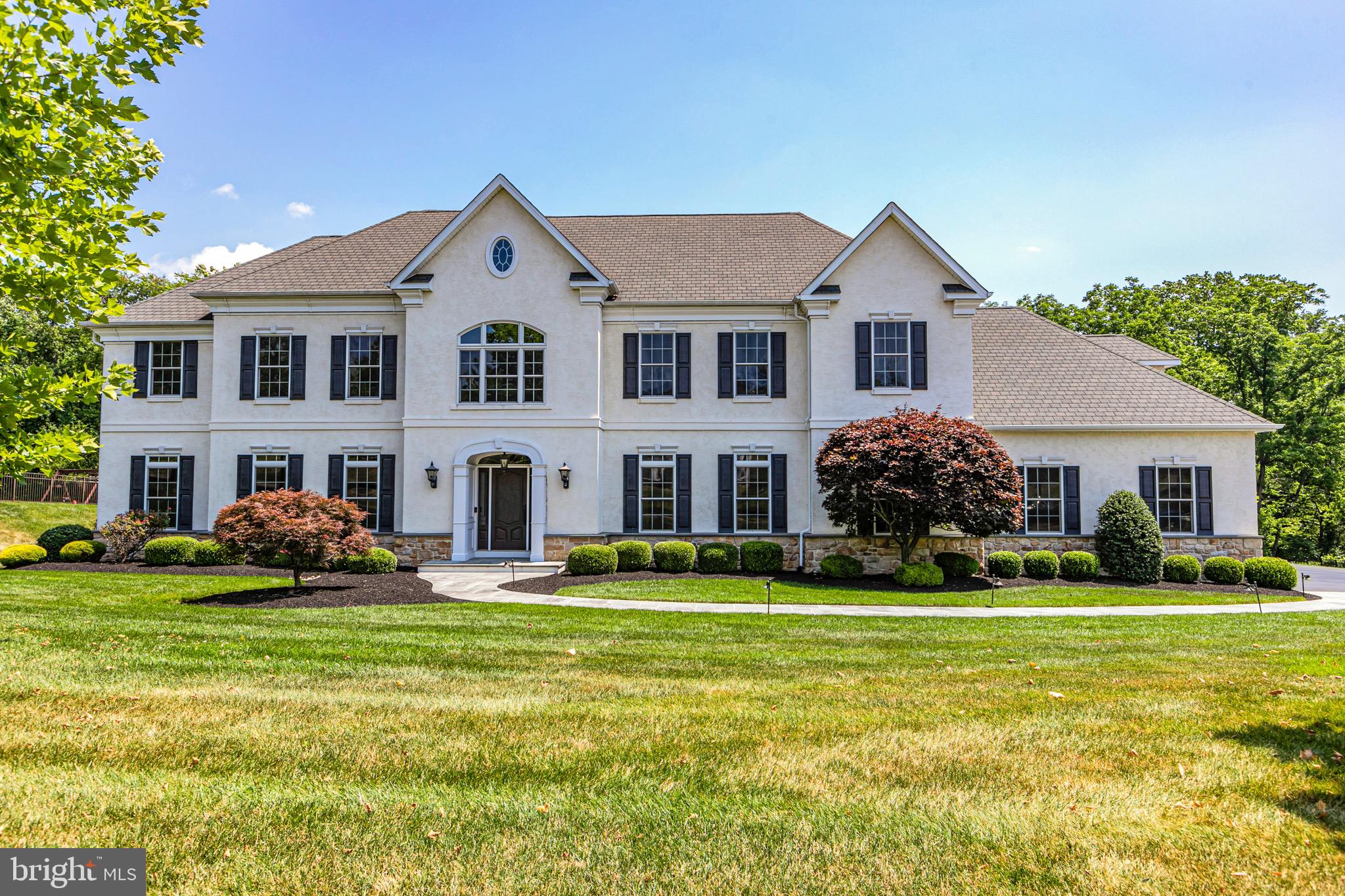 Grand European Manor style residence, its beautiful white masonry exterior proudly embraced by emerald lawns, exudes curb appeal and timeless style. Its keynotes are effortless grace, elegance and old world quality with a generous dash of luxury. A statement entry foyer is perfectly balanced with rooms on either side and views to the rear of the home. Custom features and craftsmanship are on display throughout with high ceilings and entryways, handsome built ins and gleaming hardwood floors that sweep through the first floor, uniting its spaces. The main living level offers formal living and dining rooms, study, spacious family room, gourmet kitchen with a chunky center island, top flight appliances, abundant storage and casual sun filled eating area, oversized library/office (with a nearby full bath could serve as a guest space), half bath, laundry room and two sets of stairs to the second floor. Upstairs the main bedroom is a beautiful retreat bathed in soft light and featuring a private bath and very generous walk in closet. Two other bedrooms share a bath and bedroom 4 is a suite with its own bathroom. A large bonus room could serve many purposes. Its full walk out daylight basement with sliders that open to the lower patio and stone fireplace and contains a vast open entertainment room, exercise room or 5th bedroom with a full bath and ample storage. The rear yard is accented by a backdrop of mature woodlands. Set in an exclusive cul de sac of 7 homes, the area has great commuter access to major routes in PA and NJ, nearby shopping and conveniences. Offered for sale for the first time, this finely crafted and well cared for home combines comfort, world class lifestyle and warm welcome.