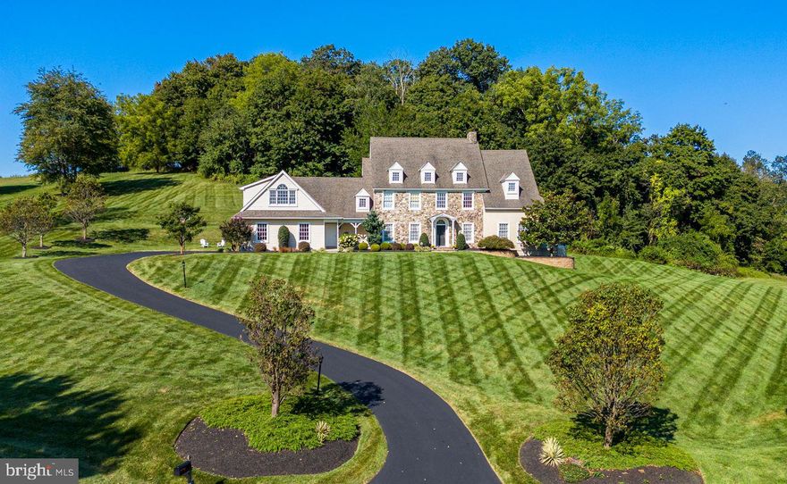 Nestled in the heart of beautiful and historic Chester Springs, this exquisite custom-built center hall colonial home offers elegance, spacious comfort, and timeless appeal on a professionally landscaped 5+ acre lot in the Cotswold Estates subdivision. No detail was overlooked with this remarkable property built in 2003, featuring extensive energy and water saving features. This beautiful and environmentally friendly and efficient home features 5 full bedrooms with 3 full and 3 half baths, a 3-car oversized garage with openers, an automatic backup generator, and over 6400 sqft of total living space located inside the award-winning Downingtown Area School District and the esteemed STEM Academy.  
Walk up the natural stone front walkway with professionally installed low voltage uplighting to the main entrance.  As you enter the home, you will be immediately impressed by the center hall foyer with two story entry and a beautiful, curved white oak stairway.   The main floor boasts 10 to 12’ ceilings, random width oak plank flooring with walnut inlays, and an open concept gourmet kitchen with dining area.  The family room has numerous built-in shelves and cabinets, and a stone, direct vent gas fireplace with reclaimed wood beam mantle.  The main floor also has formal dining and living rooms, and a conservatory/office area with a vaulted ceiling and wrap-around windows for a panoramic view of the property.
The gourmet kitchen has a Viking 4-burner LP range with griddle, Viking double ovens, Viking dishwasher, GE refrigerator/freezer with door panels to match the Century Custom kitchen cabinets, GE Built-in microwave oven, large granite countertops, Island with sink and cabinets, breakfast bar, and wet bar with sink and 24 bottle wine rack. Off the kitchen there is a powder room and mudroom with slate floors, a built-in desk/message center, built-in bench and coat hooks, and doors to the outside and garage. There is a second powder room on the first floor adjoining the foyer.
From the family room there is a back carpeted stairway to the finished walkout basement with 10 ft ceilings and a rec room, large half bath, negotiable pool table, exercise area, den, craft room, and large utility/storage spaces.
On the second floor, the Owner’s suite includes an extensive walk-in closet with built in organization system, a beautiful en suite bath, and separate sitting/reading room with windows that provide panoramic views where you can watch the sunrise.  The carpeted hallway leads to an additional 4 bedrooms with 9ft ceilings, ample closet space, and 2 additional full jack and jill bathrooms. The dormers and high windows have switched receptacles for holiday or accent lighting.  There is a second-floor laundry room with a sink and large folding table, and the attic has a partial floor and three dormer windows.
The exterior of the home features natural stone, hardiplank siding, and stucco providing a virtually maintenance free exterior.  Exit the family room through the French doors to a stone patio with stucco walls and slate caps, and a Koi Pond with a waterfall, and EP Henry hardscape stairs to the lower level. Outside the lower-level walk out doors is another stone patio.  Down the hill is your private putting green.
Close to the Turnpike, Main Line, and commuter rail stations.  Nearby recreation includes Marsh Creek State Park, numerous trail systems and parks, and historic Yellow Springs.  Close to shopping and restaurants. This “better than new” home is must-see. Don't miss the chance to experience the best of Chester Springs living in style. Schedule your private showing today and make this captivating property your own!