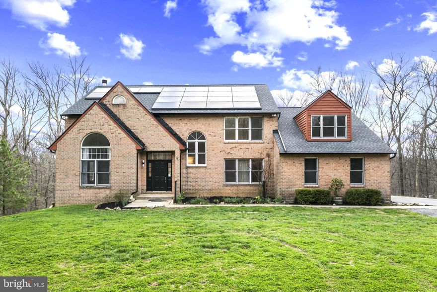 Nestled in the highly desirable Woodleaf subdivision, this custom-built brick estate offers an exceptional blend of privacy, luxury, and modern efficiency. Privately situated on 13+ secluded acres, a breathtaking 150-yard tree-lined driveway creates a grand first impression and a true sense of arrival. With over 4,000 square feet of thoughtfully designed living space, this impressive home features 5 spacious bedrooms and 4.5 baths. The well-appointed floor plan offers comfortable everyday living while seamlessly accommodating gatherings and entertaining. The expansive eat-in kitchen is a chef’s delight, complete with cooktop, wall oven, generous counter space, and abundant cabinetry. A cozy wood-burning fireplace warms the main level, creating an inviting atmosphere during cooler months. The lower level boasts a massive workshop—ideal for hobbyists, craftsmen, or creative projects. Recent upgrades provide peace of mind, including a newer HVAC system, dishwasher and brand-new water heater. The roof and gutters are only two years old! This all-electric home is designed for efficiency with leased solar panels and two Tesla backup batteries, helping to significantly reduce utility costs while providing reliable power during outages. Relax year-round in the four-season room or unwind outdoors on one of two spacious decks overlooking the serene, protected watershed acreage. The property invites outdoor adventure with room to explore, hike, and garden. A greenhouse extends your growing season, and the established chicken coop and run add to the homestead charm. Keep the family pets safe too with an invisible fence that's already installed! With county approval, there is even potential to add stables and create a private horse property. Enjoy the tranquility of country living without sacrificing convenience. This extraordinary Woodleaf estate truly offers space, sustainability, and endless possibilities.