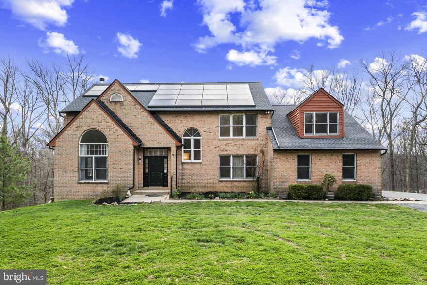 Nestled in the highly desirable Woodleaf subdivision, this custom-built brick estate offers an exceptional blend of privacy, luxury, and modern efficiency. Privately situated on 13+ secluded acres, a breathtaking 150-yard tree-lined driveway creates a grand first impression and a true sense of arrival. With over 4,000 square feet of thoughtfully designed living space, this impressive home features 5 spacious bedrooms and 4.5 baths. The well-appointed floor plan offers comfortable everyday living while seamlessly accommodating gatherings and entertaining. The expansive eat-in kitchen is a chef’s delight, complete with cooktop, wall oven, generous counter space, and abundant cabinetry. A cozy wood-burning fireplace warms the main level, creating an inviting atmosphere during cooler months. The lower level boasts a massive workshop—ideal for hobbyists, craftsmen, or creative projects. Recent upgrades provide peace of mind, including a newer HVAC system, dishwasher and brand-new water heater. The roof and gutters are only two years old! This all-electric home is designed for efficiency with leased solar panels and two Tesla backup batteries, helping to significantly reduce utility costs while providing reliable power during outages. Relax year-round in the four-season room or unwind outdoors on one of two spacious decks overlooking the serene, protected watershed acreage. The property invites outdoor adventure with room to explore, hike, and garden. A greenhouse extends your growing season, and the established chicken coop and run add to the homestead charm. Keep the family pets safe too with an invisible fence that's already installed! With county approval, there is even potential to add stables and create a private horse property. Enjoy the tranquility of country living without sacrificing convenience. This extraordinary Woodleaf estate truly offers space, sustainability, and endless possibilities.