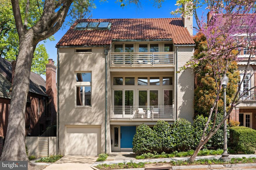 This contemporary residence offers generous scale, natural light, and a thoughtful layout across multiple levels. Clean lines, open spaces, and strong architectural elements create a home that is both functional and visually compelling. The entry foyer is spacious and filled with light, with a powder room, coat closet, and direct access to the one-car garage. A lower level just off the entry provides flexible space, well suited for a gym, office, or studio. A custom floating staircase connects the home’s main levels. The kitchen, dining, and family areas are open and flow directly to landscaped gardens and a flagstone terrace. The outdoor space includes an in-ground pool and a pergola, creating a natural extension of the living area. One level above, the formal living room features a fireplace, high ceilings, and a wall of glass opening to a balcony. The adjacent library includes built-in shelving and can function as a reading room, office, or media space. The proportions on this level allow for comfortable everyday use as well as entertaining. The primary suite occupies its own floor and overlooks the garden. The bathroom includes a soaking tub, large shower, and a walk-in closet. A private balcony adds an additional outdoor connection. The next level includes a sitting room with a fireplace and balcony, an en-suite bedroom, an additional bedroom, a hall bathroom, and laundry. The top floor offers a fourth bedroom, along with a sitting room that can easily function as a fifth bedroom. White oak floors run throughout the home, reinforcing a consistent and clean aesthetic. The property is located on Bancroft Place, a quiet one-way street in the embassy district. It is within walking distance of Mitchell Park, Dupont Circle, restaurants, shops, museums, and cultural institutions. A well-designed home in a highly regarded location, offering space, light, and flexibility.